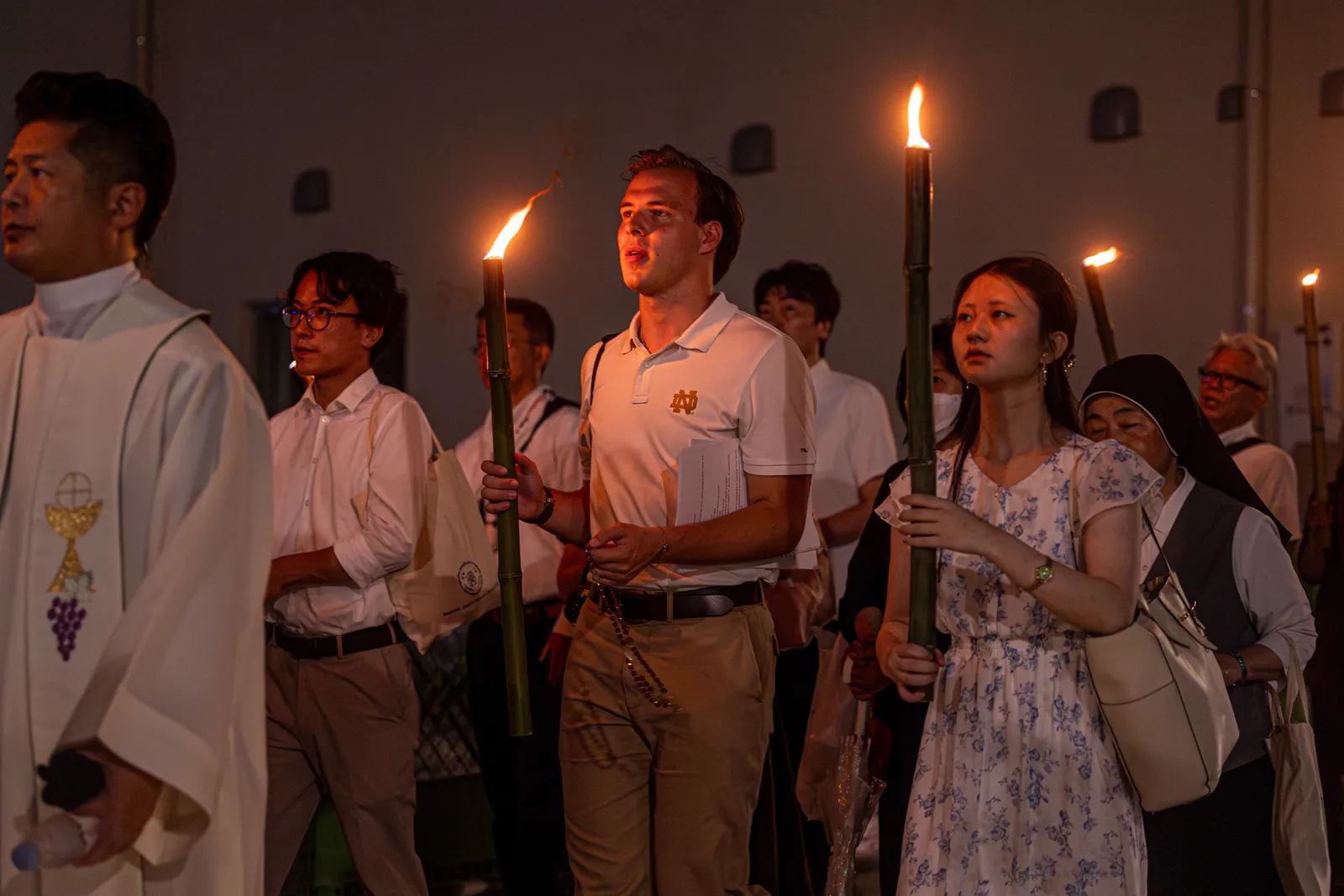 La gente participa en una procesión con antorchas al Parque de la Paz de Nagasaki. La catedral de Urakami, que se ve al fondo, fue reconstruida y dedicada en 1959 en el sitio de la catedral original destruida en el bombardeo del 9 de agosto de 1945. En la procesión participaron estudiantes universitarios estadounidenses integrantes de una Peregrinación de Paz para conmemorar los aniversarios de los bombardeos atómicos de Hiroshima y Nagasaki.