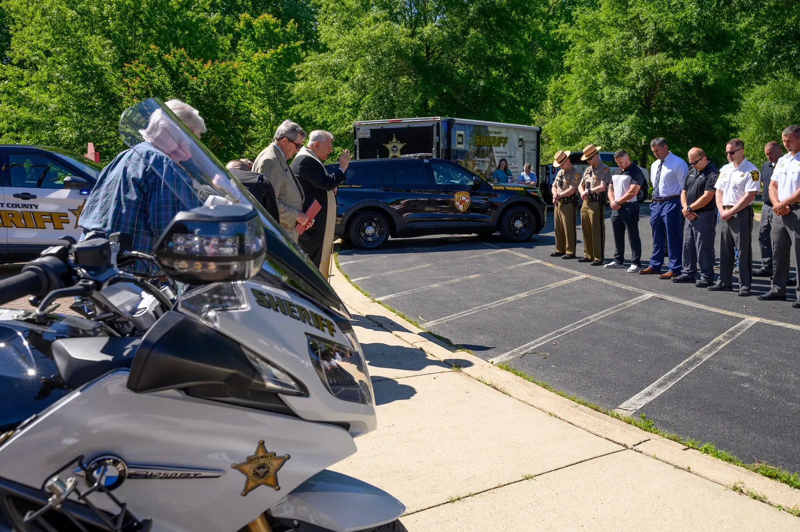 Msgr. Karl Chimiak blesses law enforcement officers and their vehicles during a blessing of the fleet ceremony as members of the Calvert County Sheriff’s Office and Maryland State Police bow their heads in prayer. (Photo courtesy of Nicole Olea)