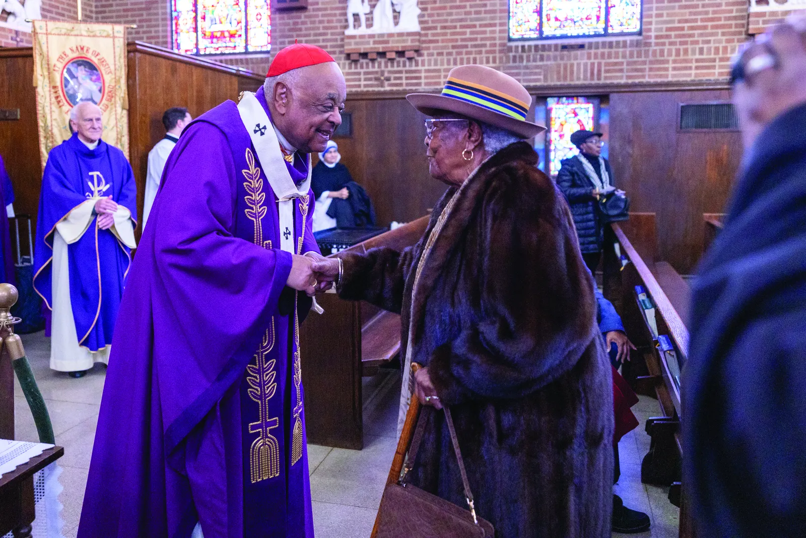 Above and below, Cardinal Wilton Gregory greets parishioners of St. Francis Xavier Church in Southeast Washington after celebrating a Dec. 1 Mass there to conclude the yearlong celebration of the parish’s 100th anniversary. (CS photos by Mihoko Owada)