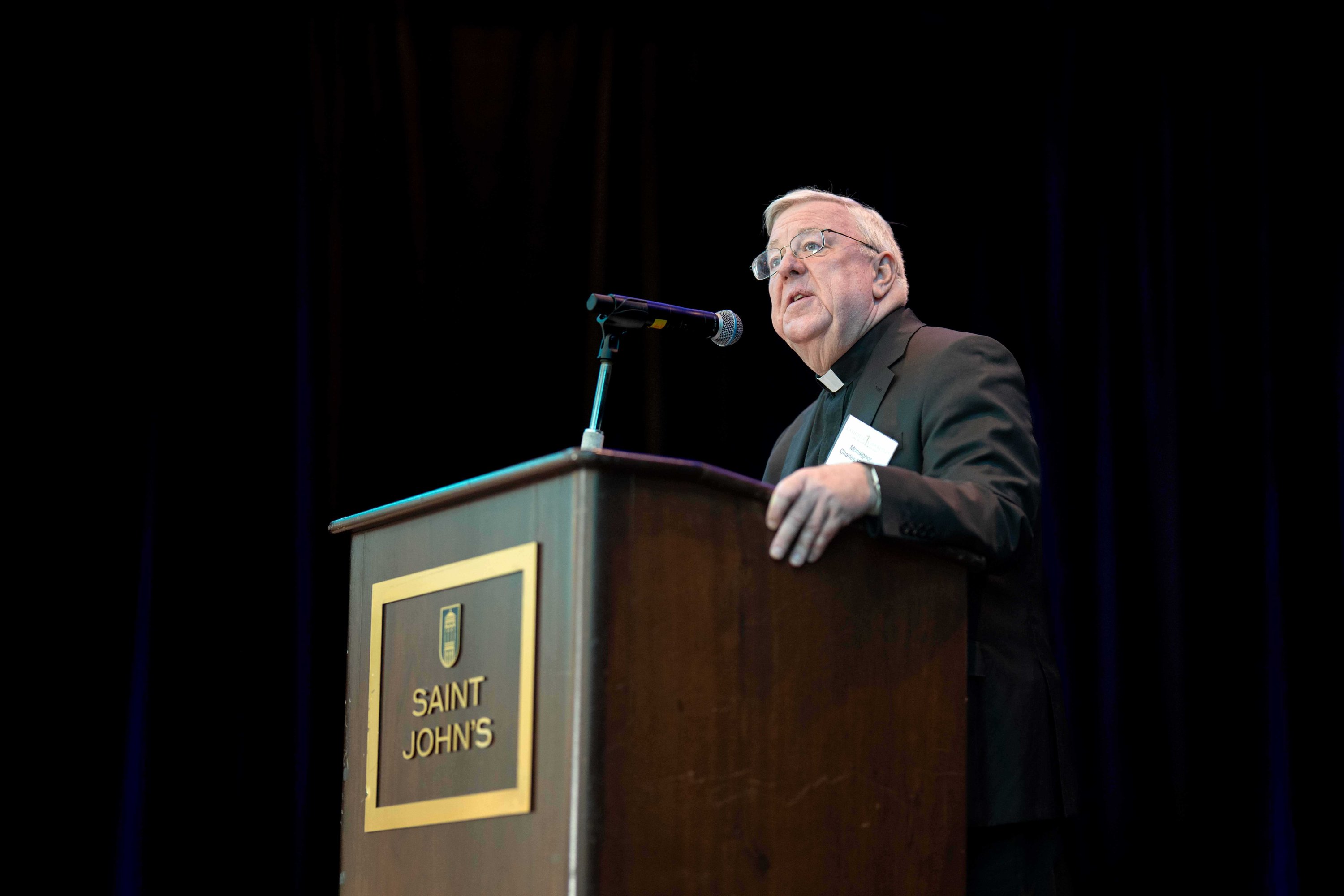 Monsignor Charles Kosanke speaking at a podium, 2026 Leonard R. Jagels Outstanding Individual Award Winner