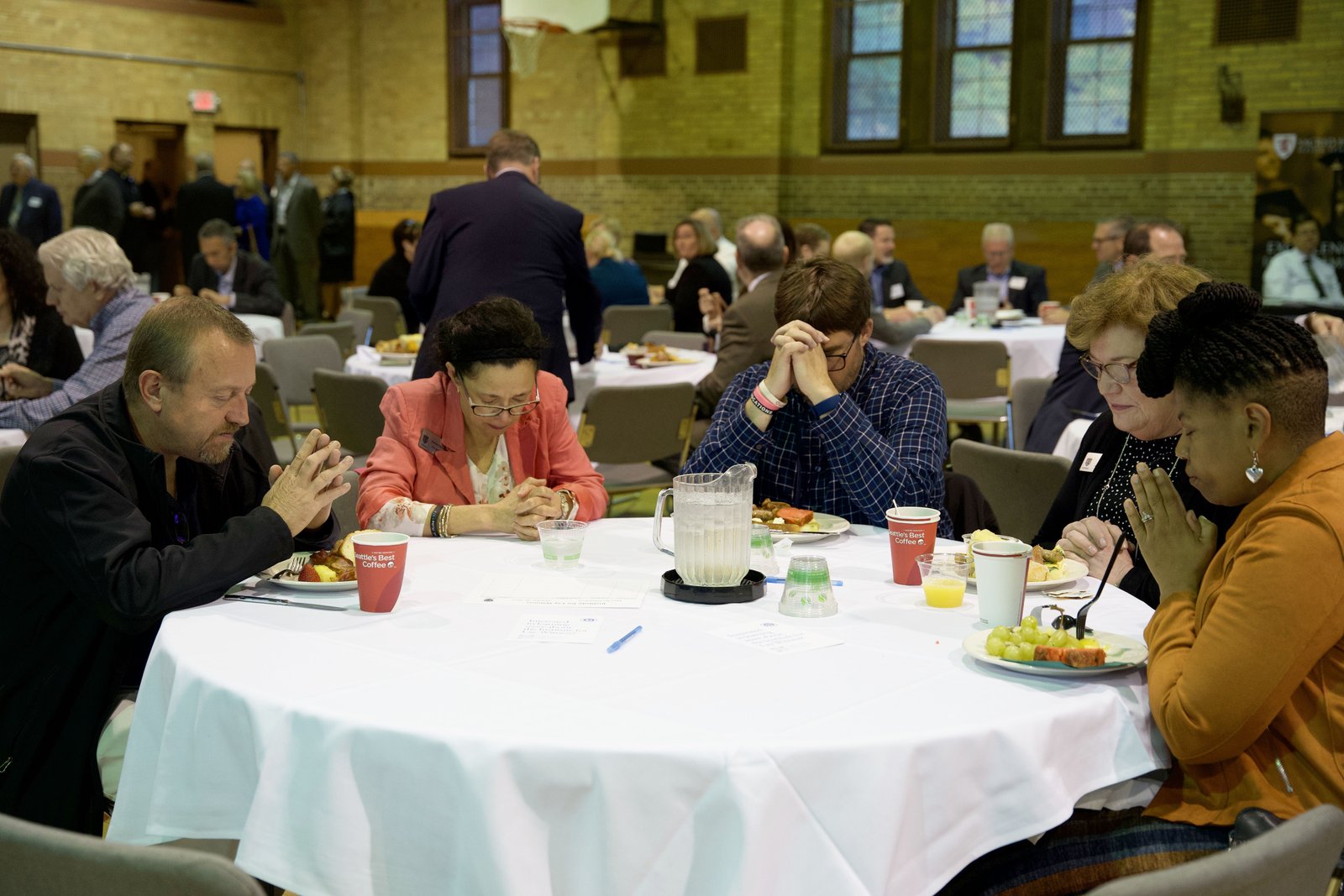 Profesionales católicos rezan juntos durante un almuerzo después de la Misa, en el gimnasio de Sacred Heart. A pesar de las presiones que enfrentan las empresas, desde la inflación hasta el empleo, la fe católica basa las decisiones en la dignidad de la persona humana, dijo el obispo Fisher.