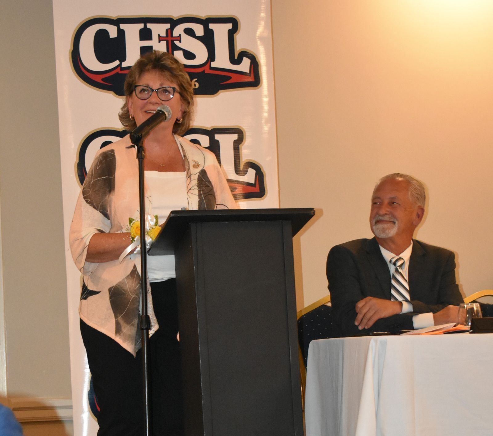 Sr. Lenore Pochelski, IHM, head of Marian High School, responds to her selection as the Ed Lauer Person of the Year at the Catholic League Hall of Fame banquet. “There is not a school motto anywhere that fits their head of school more appropriately than Marian’s does: ‘A Strong Women of Mind and Heart,’”  said CHSL Director Vic Michaels (seated). (Photo courtesy of Pat O’Leary Knipper)