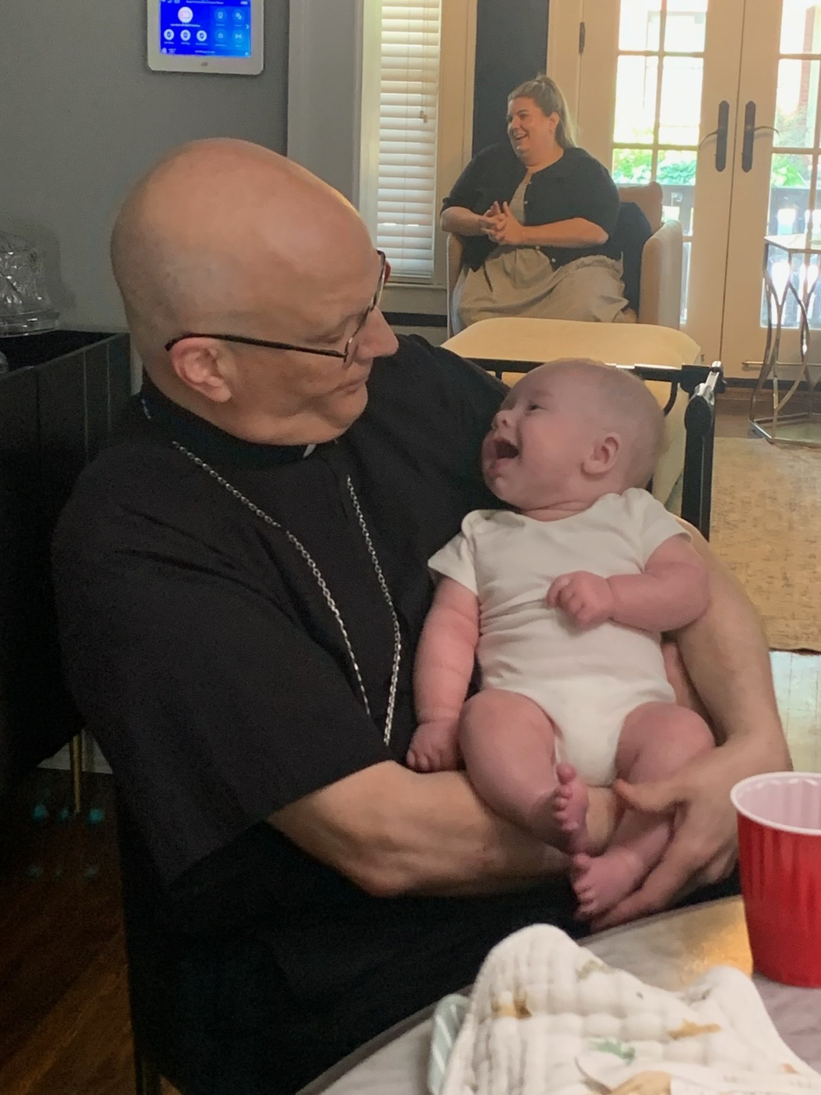 William laughs as Archbishop Weisenburger holds him during a reception following the baptism.