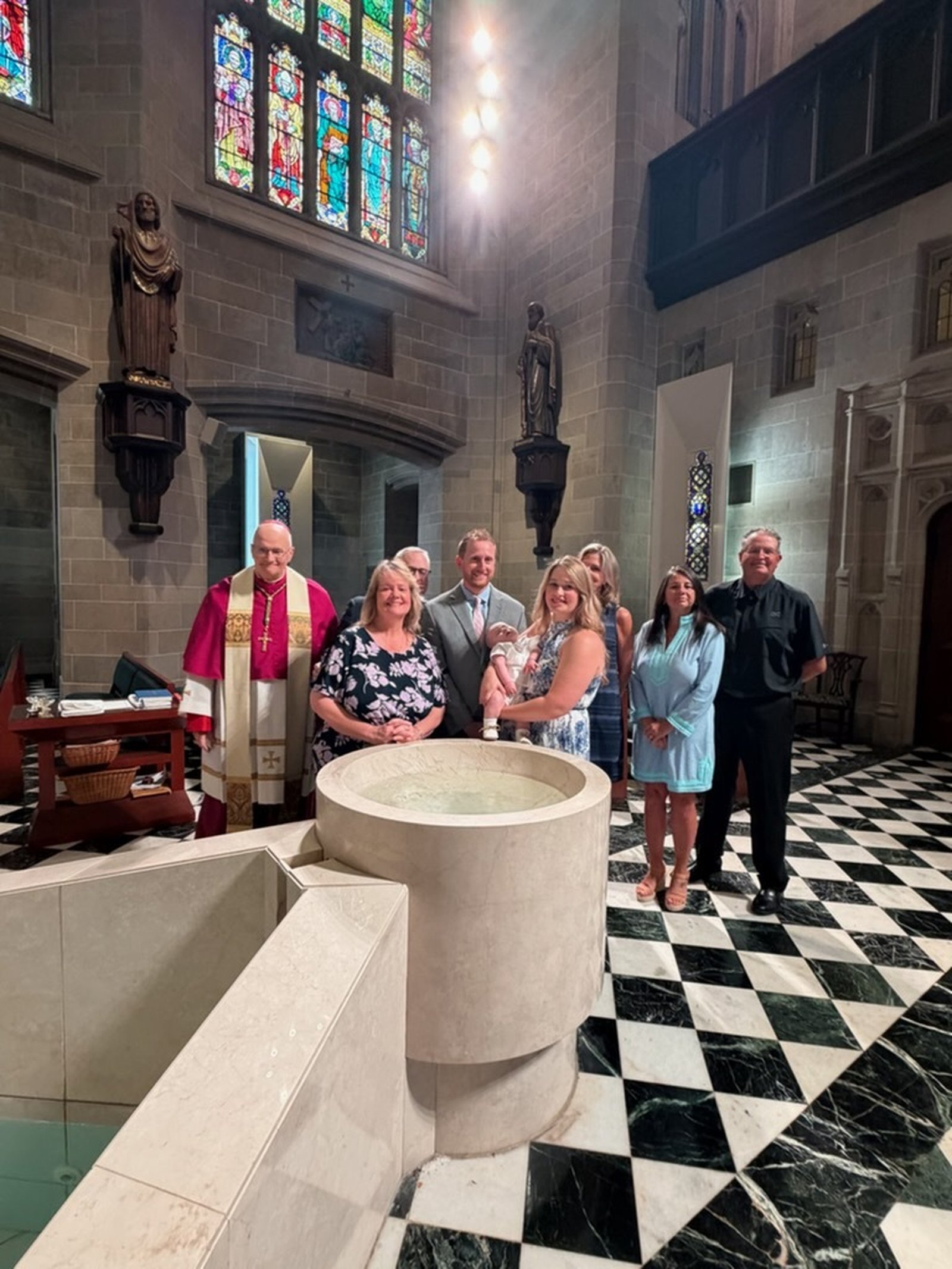 William’s parents, godparents and family members smile for a photo with Archbishop Weisenburger following the baptism.