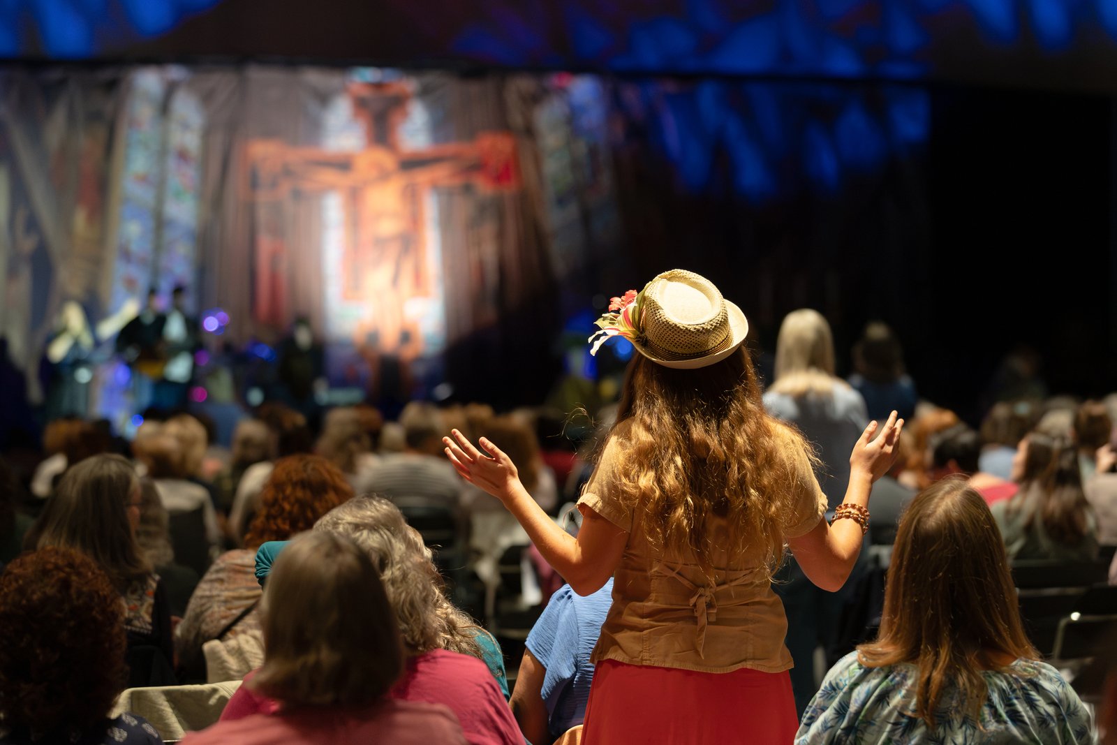 A woman lifts her hands in praise as a worship band plays during the annual Michigan Catholic Women's Conference in Lansing on Oct. 10.