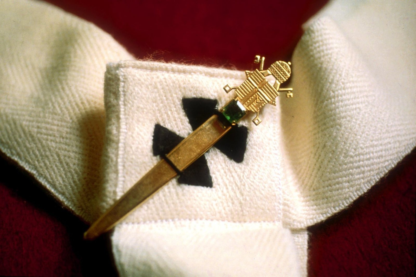 A pin decorated with the seal of Pope John Paul II is shown in a close-up view of a wool pallium. Given to new archbishops, the pallium symbolizes the pope's concession of authority and communion to the heads of major local churches. (CNS photo from Catholic Press Photo)