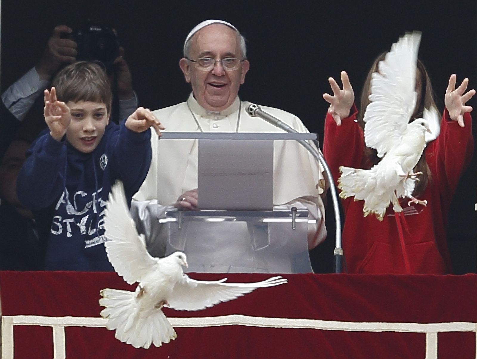 Pope Francis watches as children release doves from the window of his studio overlooking St. Peter's Square at the Vatican Jan. 26. The two young people at his side launched doves to highlight the church’s call for peace in the world. (CNS photo/Paul Haring)