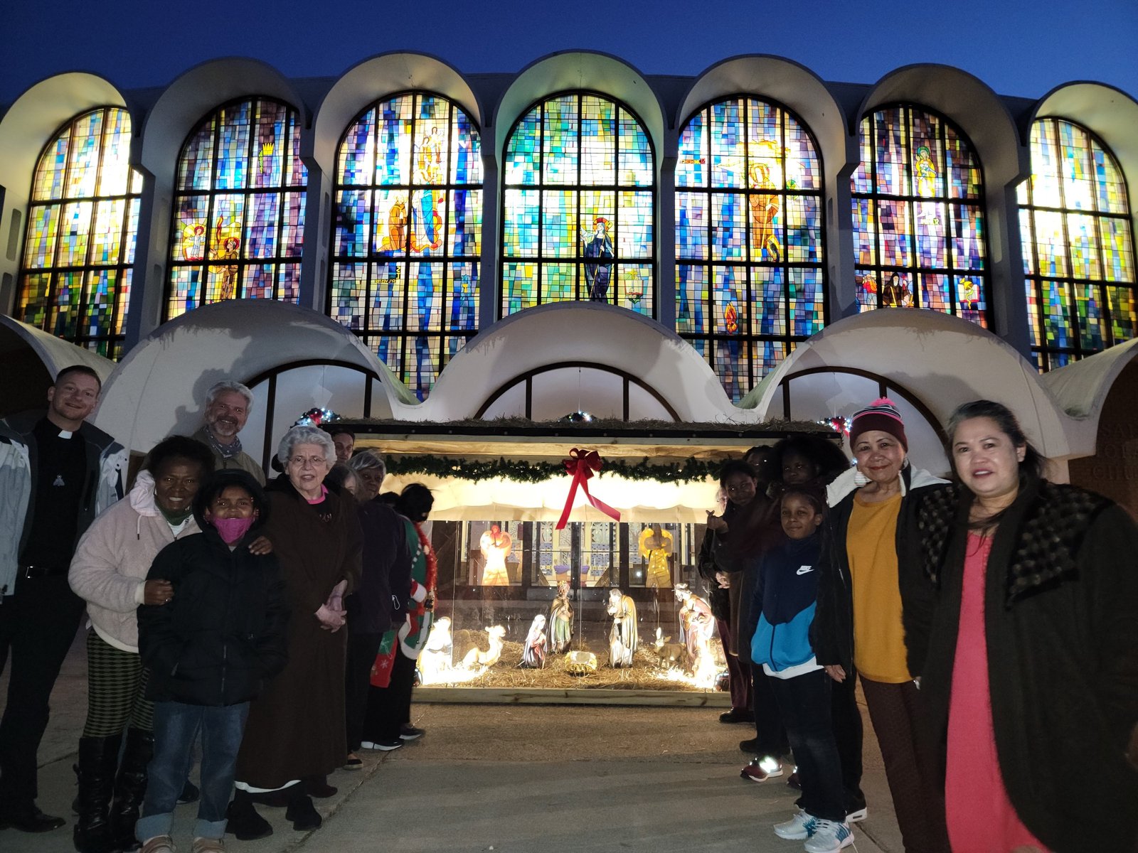 Feligreses de St. Scholastica posan frente al nuevo Nacimiento de su parroquia. El padre Lowe dijo que ya ha generado oportunidades de evangelización, ya que los vecinos y transeúntes se detienen a mirar con asombro.