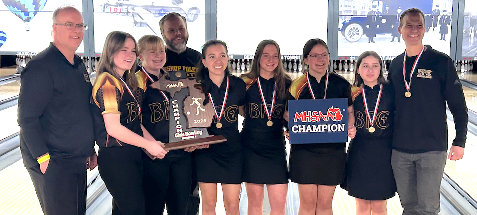 The Madison Heights Bishop Foley girls bowling team won three best-of-five Baker matches to capture the MHSAA’s Division 3 championship, the school’s first in history. Victory smiles are worn by (from the left) Coach Alan Thibodeau, senior Isabella Brunt, senior Erica Surratt, Coach Mike Madsen, senior Madelyn Kubacki, sophomore Jacey Thibodeau, freshman Teresa Schudt, freshman Charlotte Grems, and Head Coach Bradford Grems. (Photo courtesy of MHSAA.com)