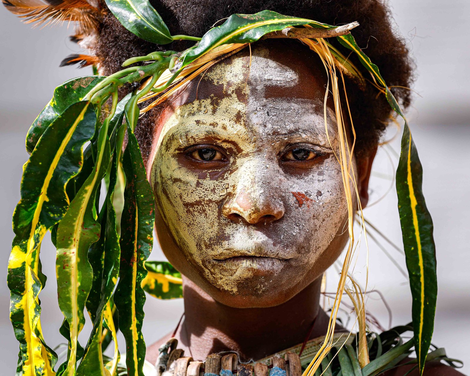 A young indigenous woman with her face painted with traditional markings, wears a headdress made of leaves and feathers during Pope Francis’ visit to the School and Queen of Paradise Hall in Port Moresby, Papua New Guinea, Sept. 8, 2024. (CNS photo/Lola Gomez)