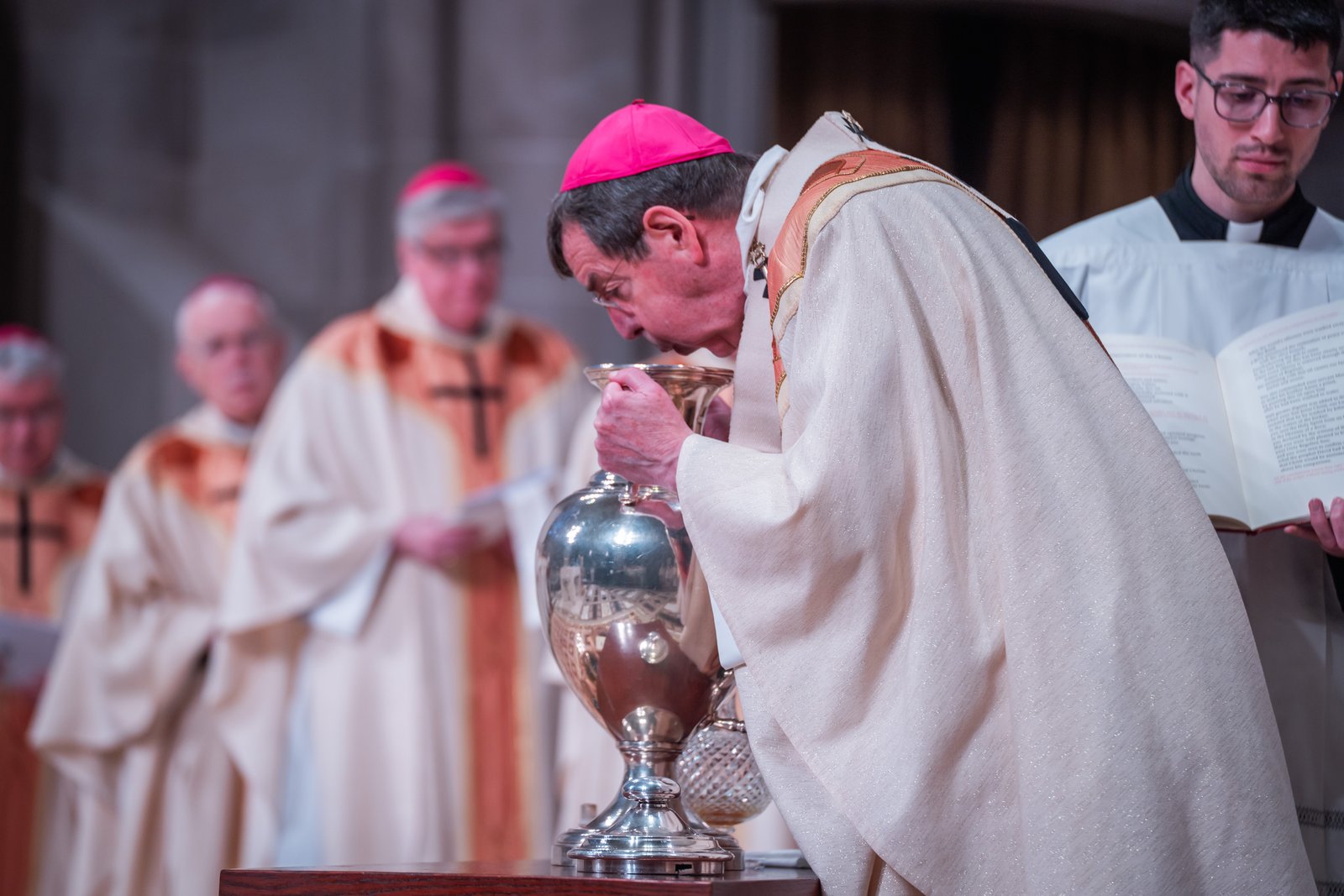 Archbishop Vigneron blows into the vessel containing the Sacred Chrism to bless it during the Chrism Mass on March 28, Holy Thursday, at the Cathedral of the Most Blessed Sacrament in Detroit. The Chrism oil, along with the Oil of the Sick and Oil of Catechumens, will be distributed to parishes across the Archdiocese of Detroit for use in the sacraments of baptism, confirmation and anointing of the sick throughout the next year. (Photos by Valaurian Waller | Detroit Catholic)