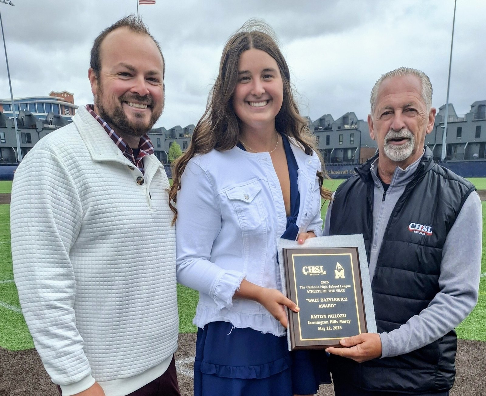 Kaitlyn Pallozzi of Mercy High School in Farmington Hills, is the 2025 Walt Bazylewicz Female Athlete of the Year. She is presented with the award by Brandon Malinowski (left), Mercy's athletic director, and CHSL director Vic Michaels.