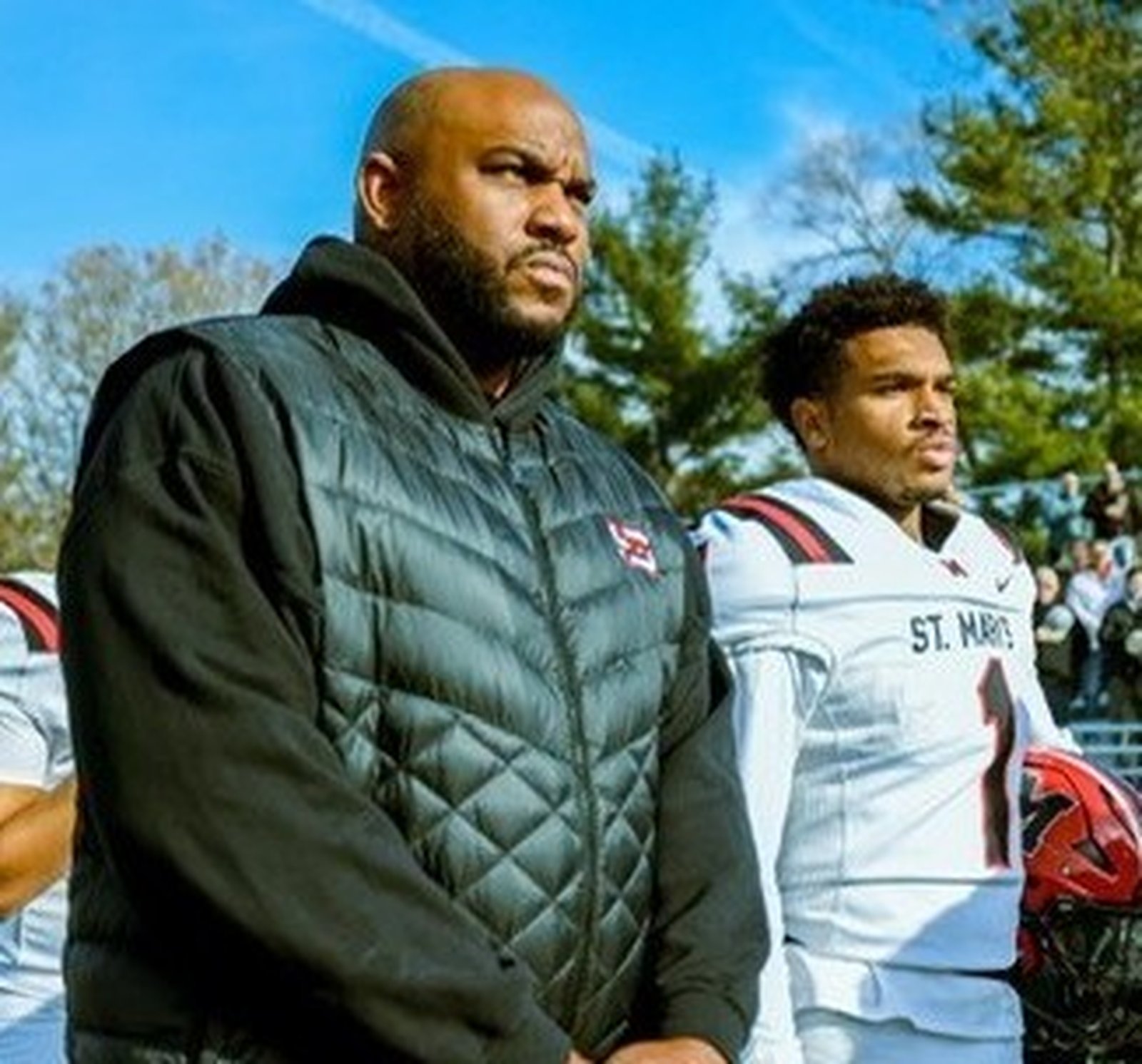 Father and son, Jermaine and Jabin Gonzales, pause at the playing of the national anthem before a game earlier this fall. Both were quarterbacks for St. Mary’s Prep state champions: Jermaine in 1999, Jabin this year. “I really was thinking how special it is to be able to do this with my son,” Jermaine said. (Photo courtesy of Stephanie Gonzales)