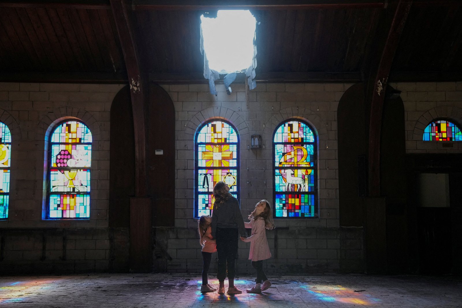 A woman and children look inside the damaged St. Mary of the Assumption Church at the very southern edge of Chicago May 9, 2025. While he was growing up, Pope Leo XIV attended Mass with his family at the church, which has been vacant since 2011 and is now in the planning stages for a possible community center, workers' training program and place of worship for area church congregations. (OSV News photo/Carlos Osorio, Reuters)