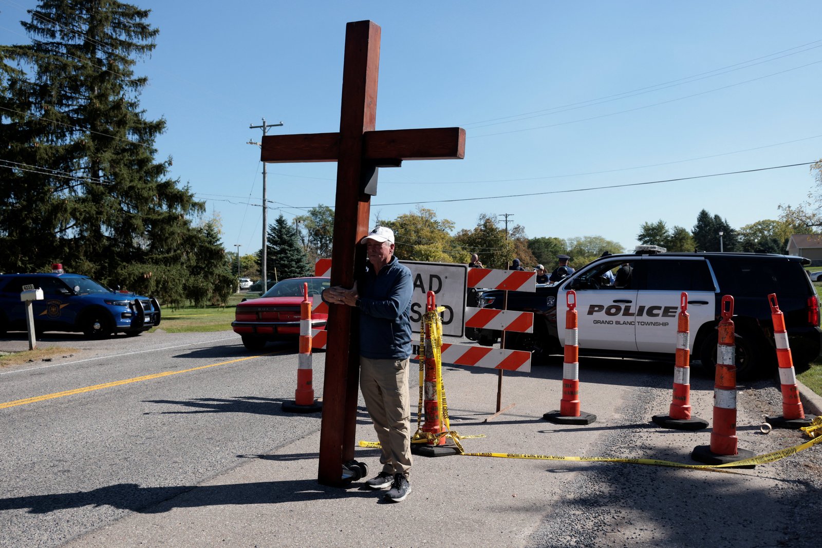 Dan Bradley holds a 10-foot cross near the scene of a mass shooting which took place at the Church of Jesus Christ of Latter-day Saints, in Grand Blanc, Mich., Sept. 29, 2025. (OSV News photo/Rebecca Cook, Reuters)