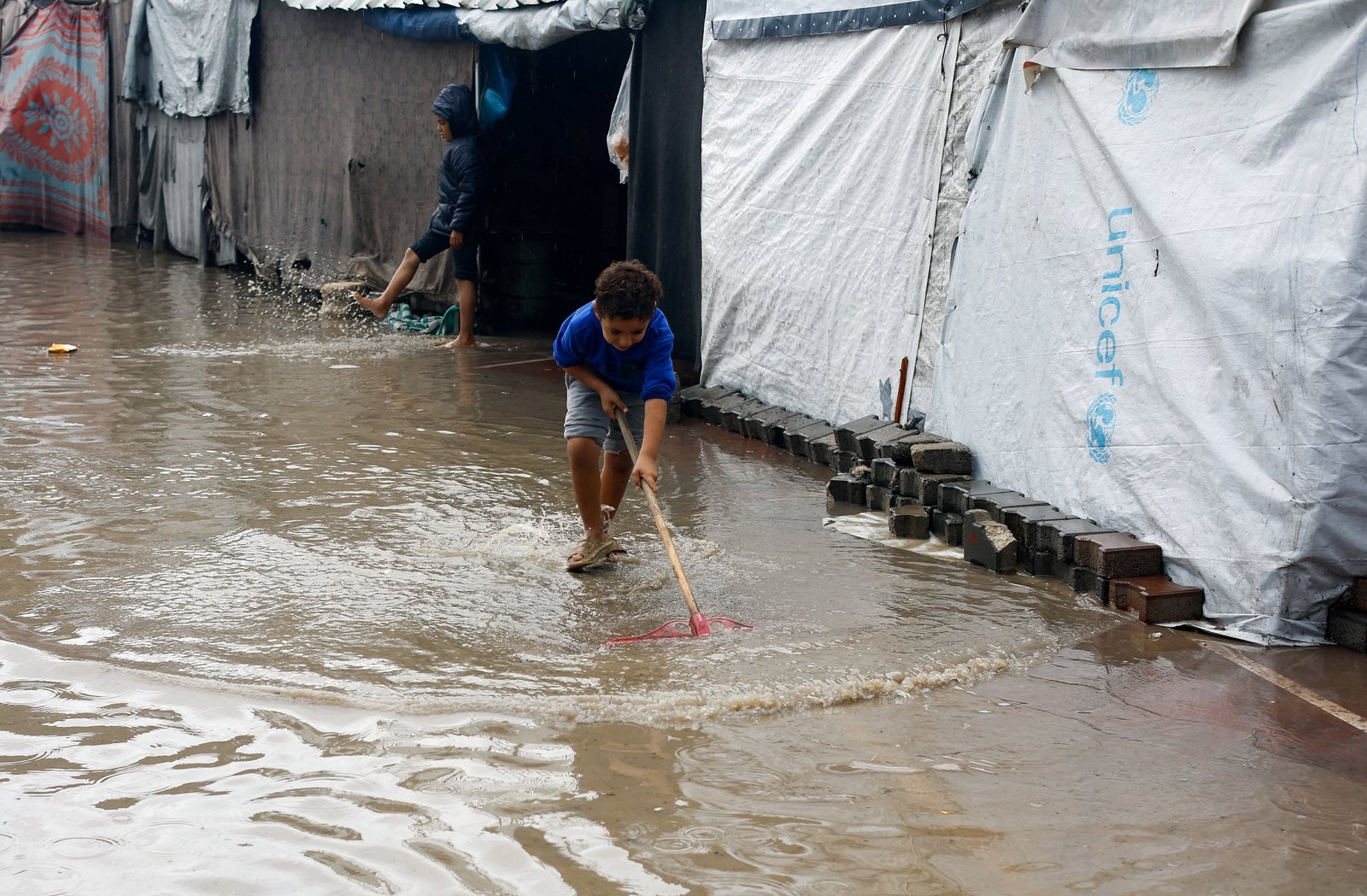 Displaced Palestinian children stand in flood water as they shelter at a flooded tent camp during a rainy day in Gaza City Nov. 25, 2025. (OSV News photo/Mahmoud Issa, Reuters)