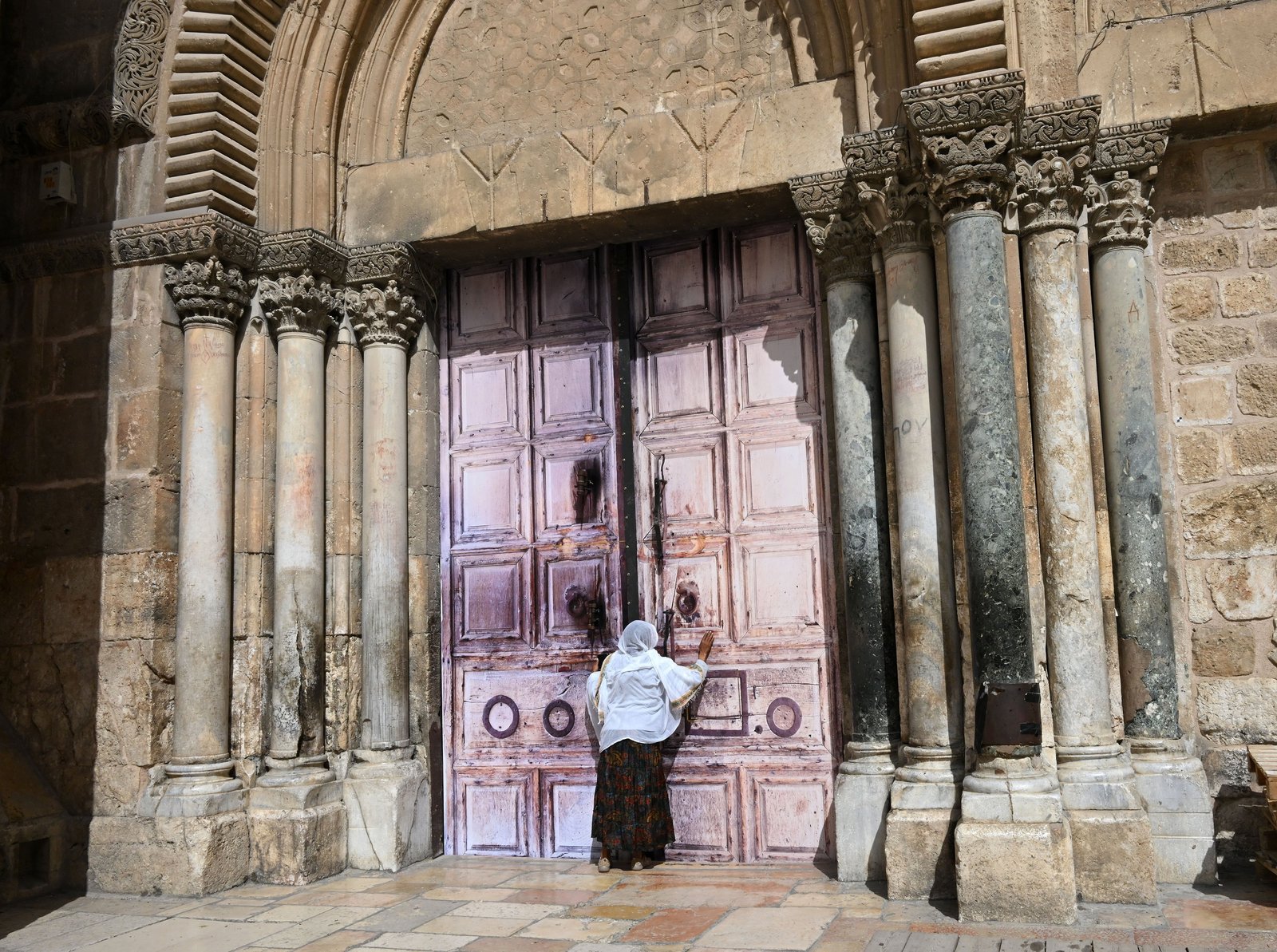 An Ethiopian Christian woman prays at the locked doors of the Church of the Holy Sepulcher in the Old City of Jerusalem March 4, 2026, on day five of the U.S.-Israel war with Iran. Besides the church, other religious sites as well as stores were locked shut by order of the Israeli government as Iranian ballistic missiles were fired at Israel. (OSV News photo/Debbie Hill)