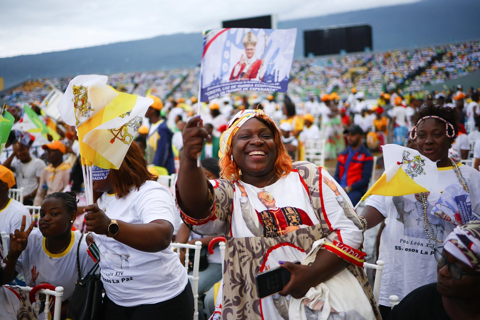 Una mujer agita una bandera con la imagen del papa León XIV antes de la llegada del pontífice para celebrar la Misa final de su viaje apostólico a África en el estadio de Malabo, en Guinea Ecuatorial, el 23 de abril de 2026. (Foto OSV News/Guglielmo Mangiapane, Reuters)