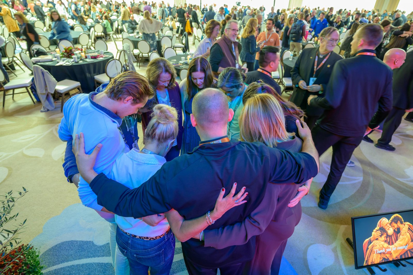 Conference attendees circle together in prayer.