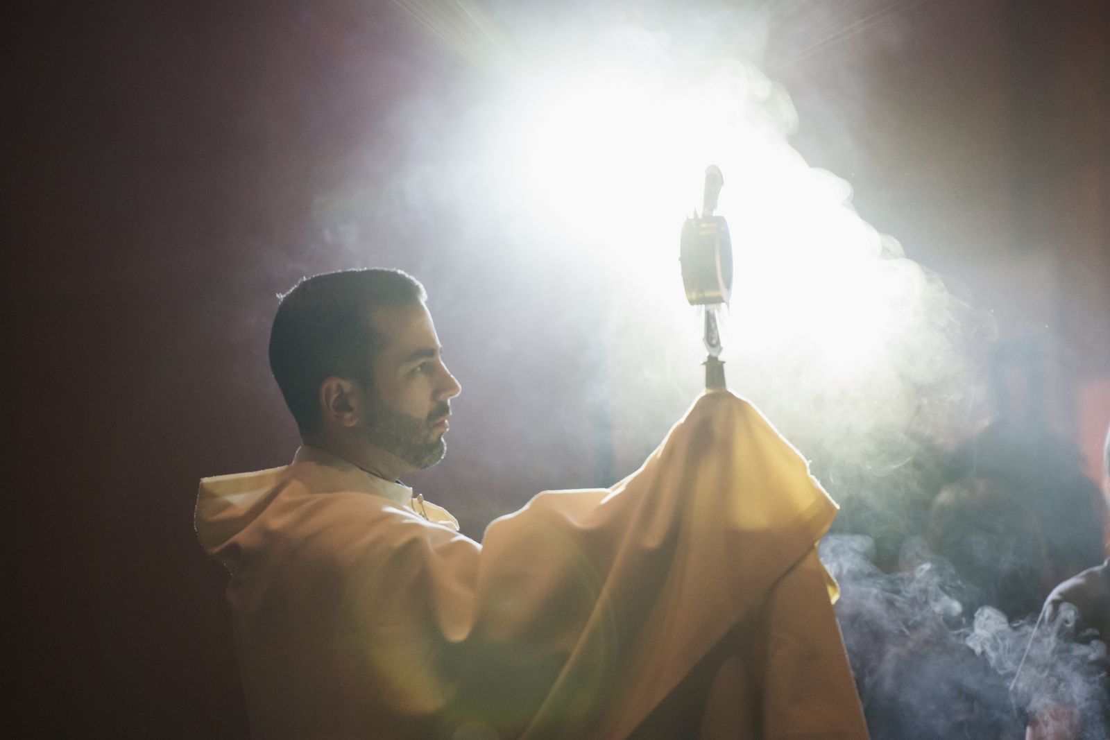 Fr. Mario Amore, director of evangelization and missionary discipleship for the Archdiocese of Detroit, elevates the Blessed Sacrament in a monstrance as teens worship during adoration. (Leah Butalid | Detroit Catholic)