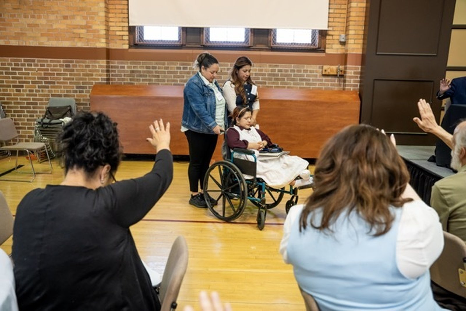 Participants of the Witness to Hope: Pastoral Care of Immigrant Communities conference at Sacred Heart Major Seminary pray over Daris Bartolon and her daughter, Maddeline. Daris and her daughter fled their native Guatemala in order to get away from her domestic abuser. She has a court date June 1 to hear her plea for asylum.