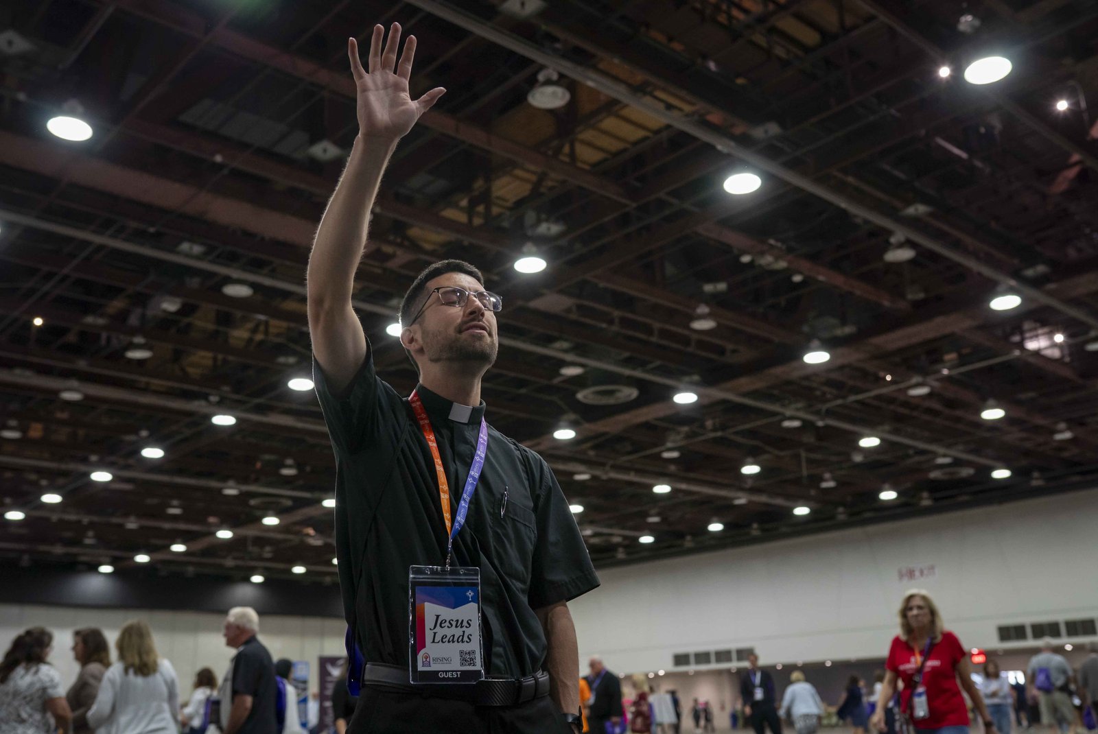 A priest raises his hand in praise. (Valaurian Waller | Detroit Catholic)