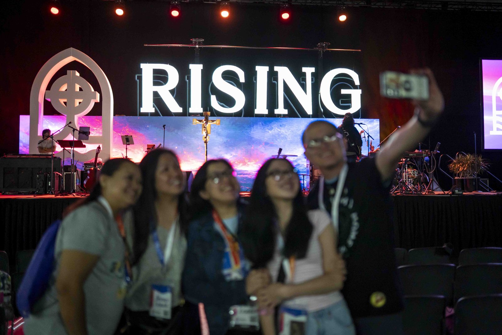 Un grupo de católicos posa para una foto frente al escenario durante el Reavivamiento inaugural «Rising from the Ashes» el 22 de julio en el Huntington Place, en el centro de Detroit. (Valaurian Waller | Especial para Detroit Catholic)