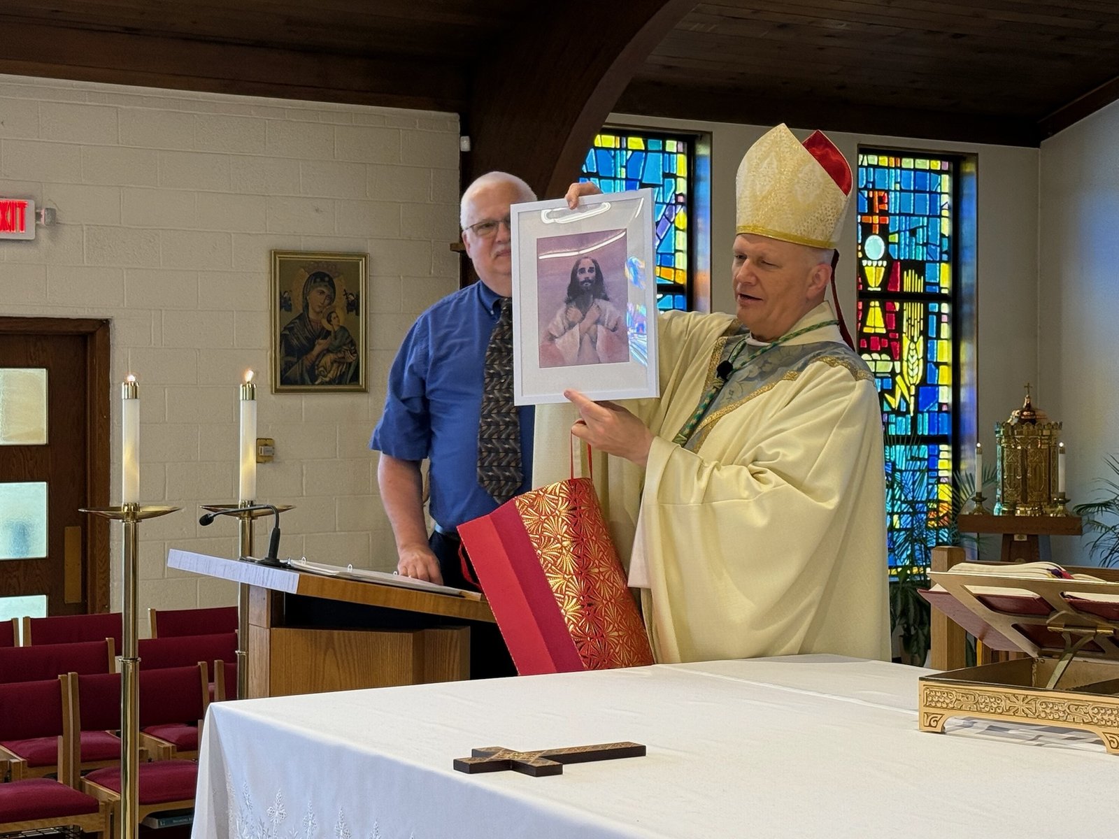 The archbishop holds a picture of Jesus signing "I love you," a gift from the local Deaf Catholic community at Holy Innocents-St. Barnabas Parish.
