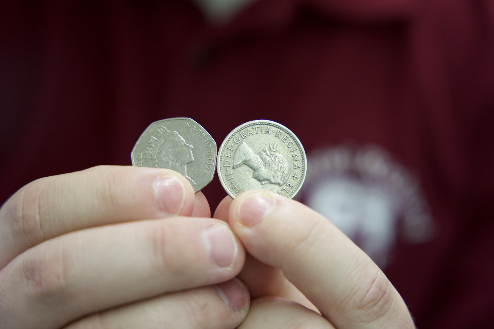 Rutkowski holds up British coins with Queen Elizabeth's image engraved on them, from his large collection of British money from over the course of her reign.