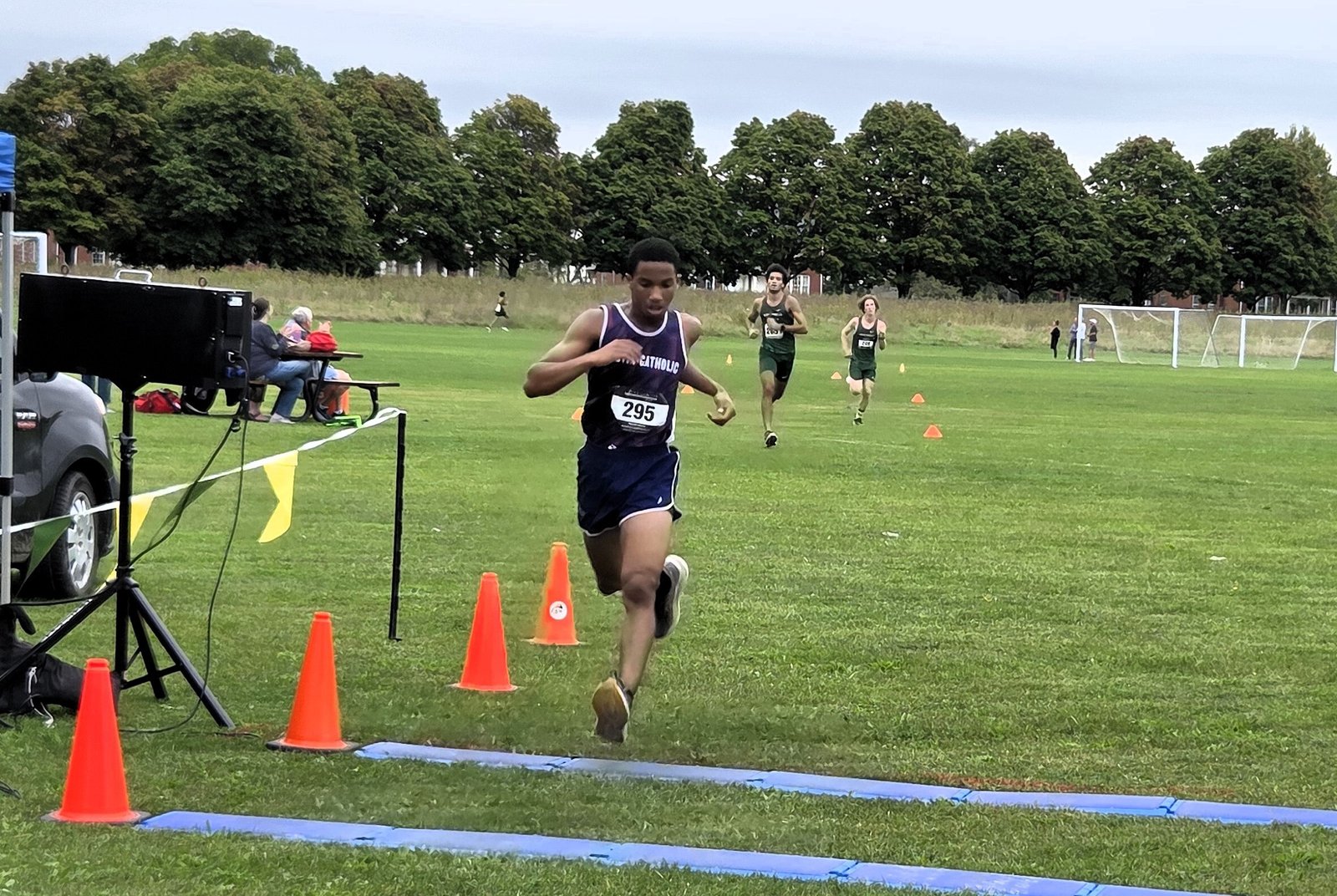 Austin Catholic sophomore Gavin Bowers crosses the finish line in first place at the Cardinal Division jamboree race on Sept. 16 in 17:42.1, just ahead of two challengers from Ann Arbor Greenhills.