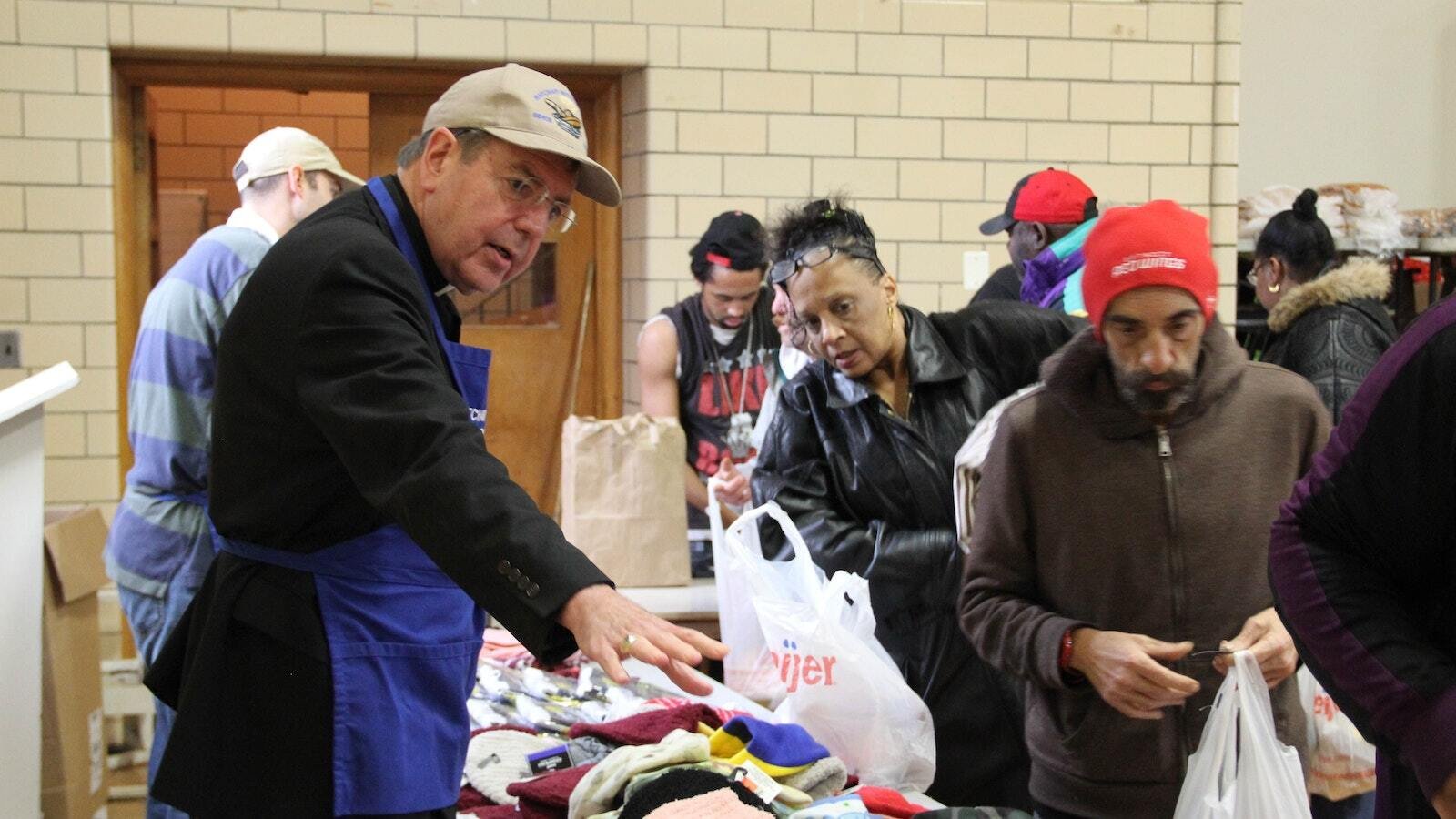 El Arzobispo Vigneron ayuda a repartir gorros, guantes y bufandas en el Matchan Nutrition Center en Pontiac el 22 de diciembre de 2016. El comedor comunitario, que da de comer a unas 500 personas todos los martes y jueves, se encuentra en el gimnasio de la St. Vincent de Paul Church, que forma parte de la St. Damien of Molokai Parish. (Jonathan Francis | Foto de archivo de Detroit Catholic)