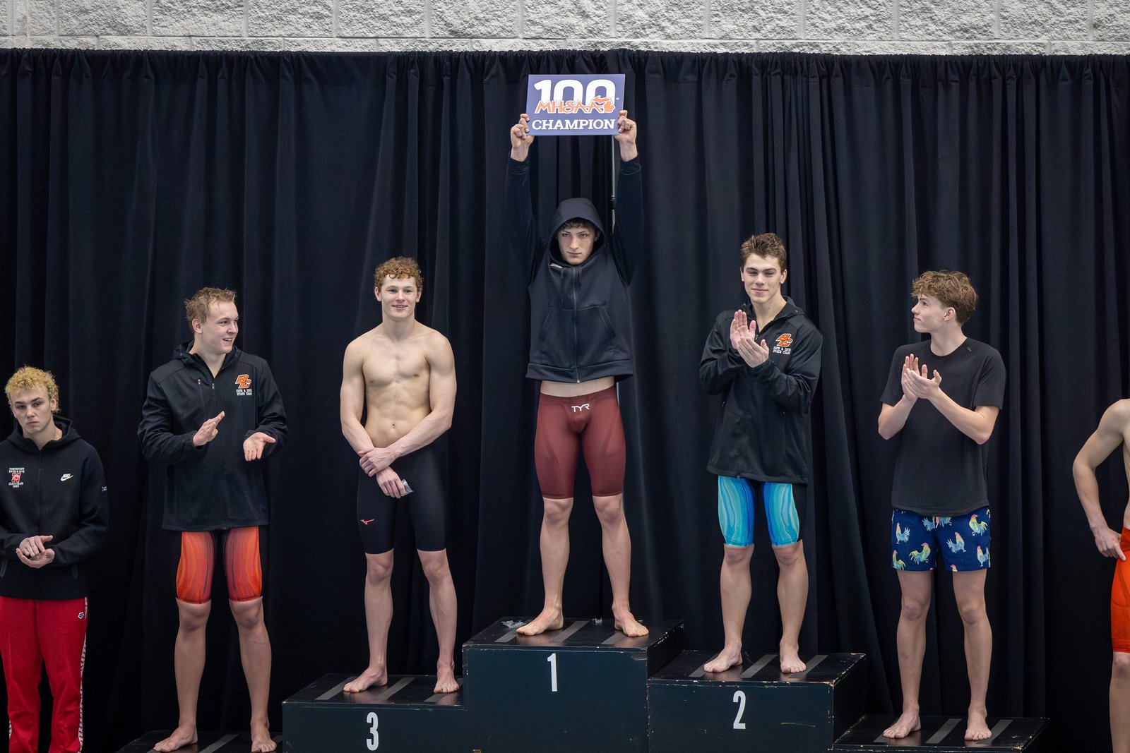 Senior Patrick MacKillop proudly shows off his state championship award sign after claiming the top spot in the breaststroke, one of five races won by University of Detroit Jesuit swimmers. (Photo courtesy of Steven Tack)