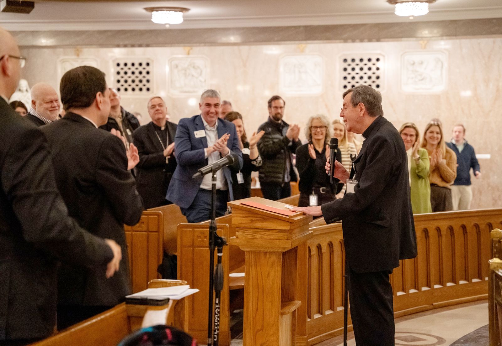 Members of the archdiocesan curia applaud outgoing Detroit Archbishop Allen H. Vigneron after he addressed staff following morning prayer at St. Aloysius Church in Detroit on Feb. 12. Until Archbishop-designate Edward J. Weisenburger's March 18 installation, Archbishop Vigneron will serve as apostolic administrator of the Archdiocese of Detroit.