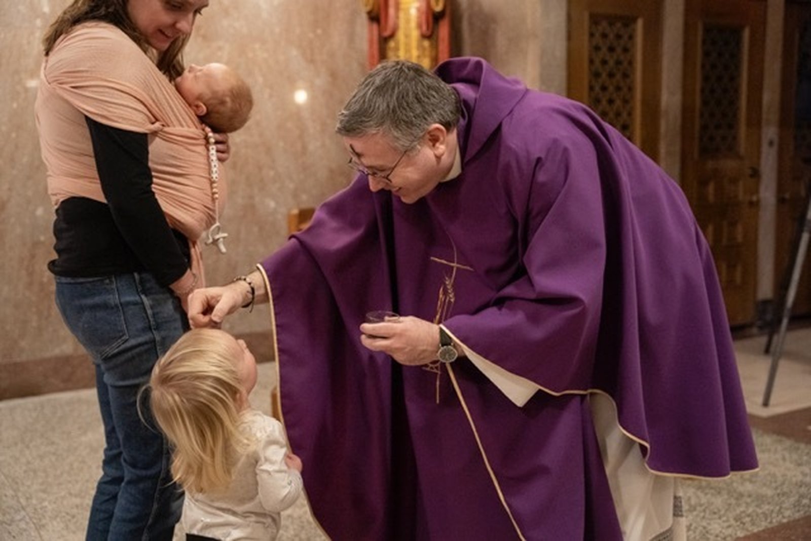 Fr. Timothy Wezner imposes ashes on the forehead of a young girl during Ash Wednesday Mass at St. Aloysius.