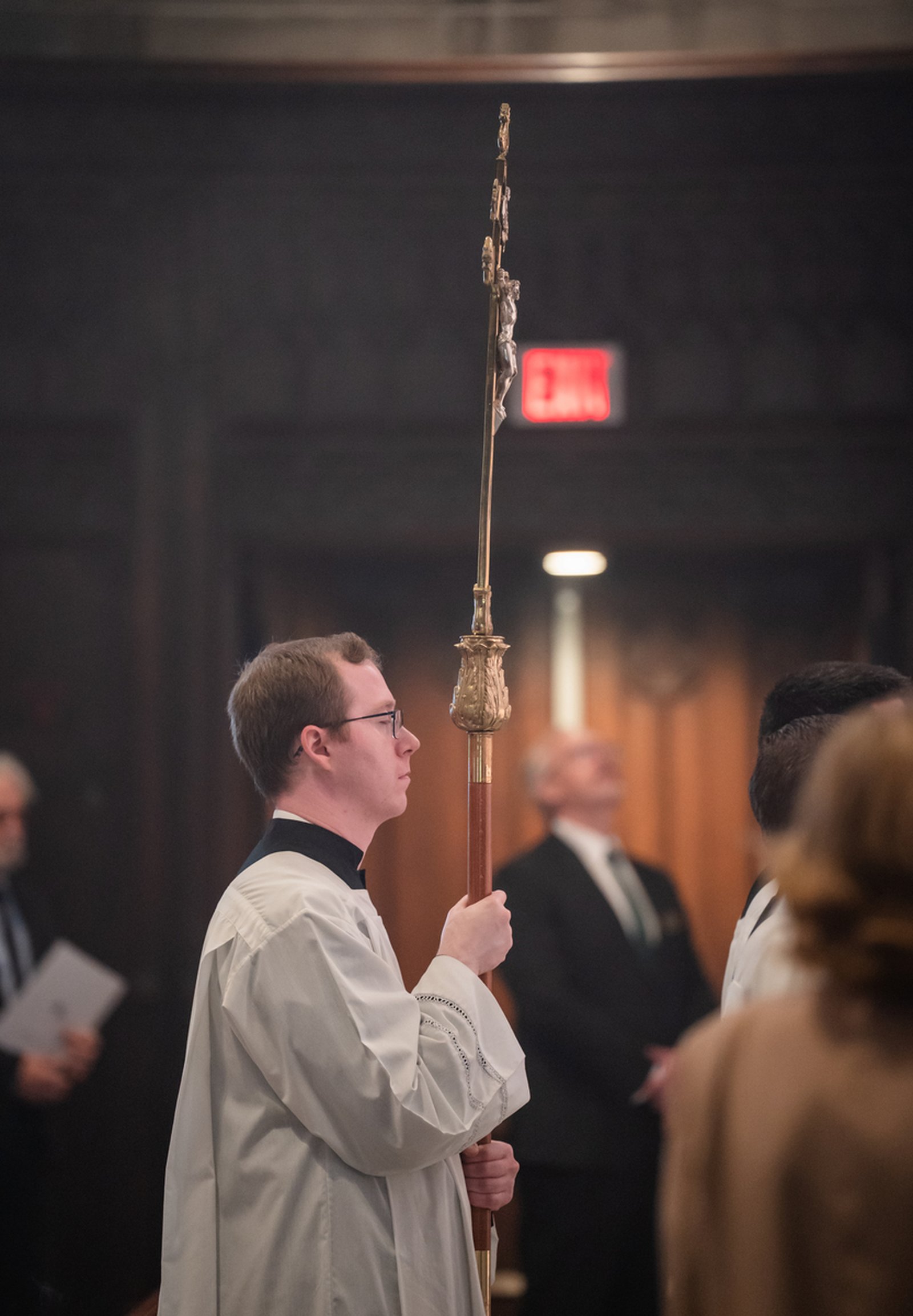 An altar server carries a crucifix in procession during the funeral liturgy. Never one to shy from his cross, Archbishop Byrnes' gratefully accepted whatever God gave him in life, Fr. Riccardo said.