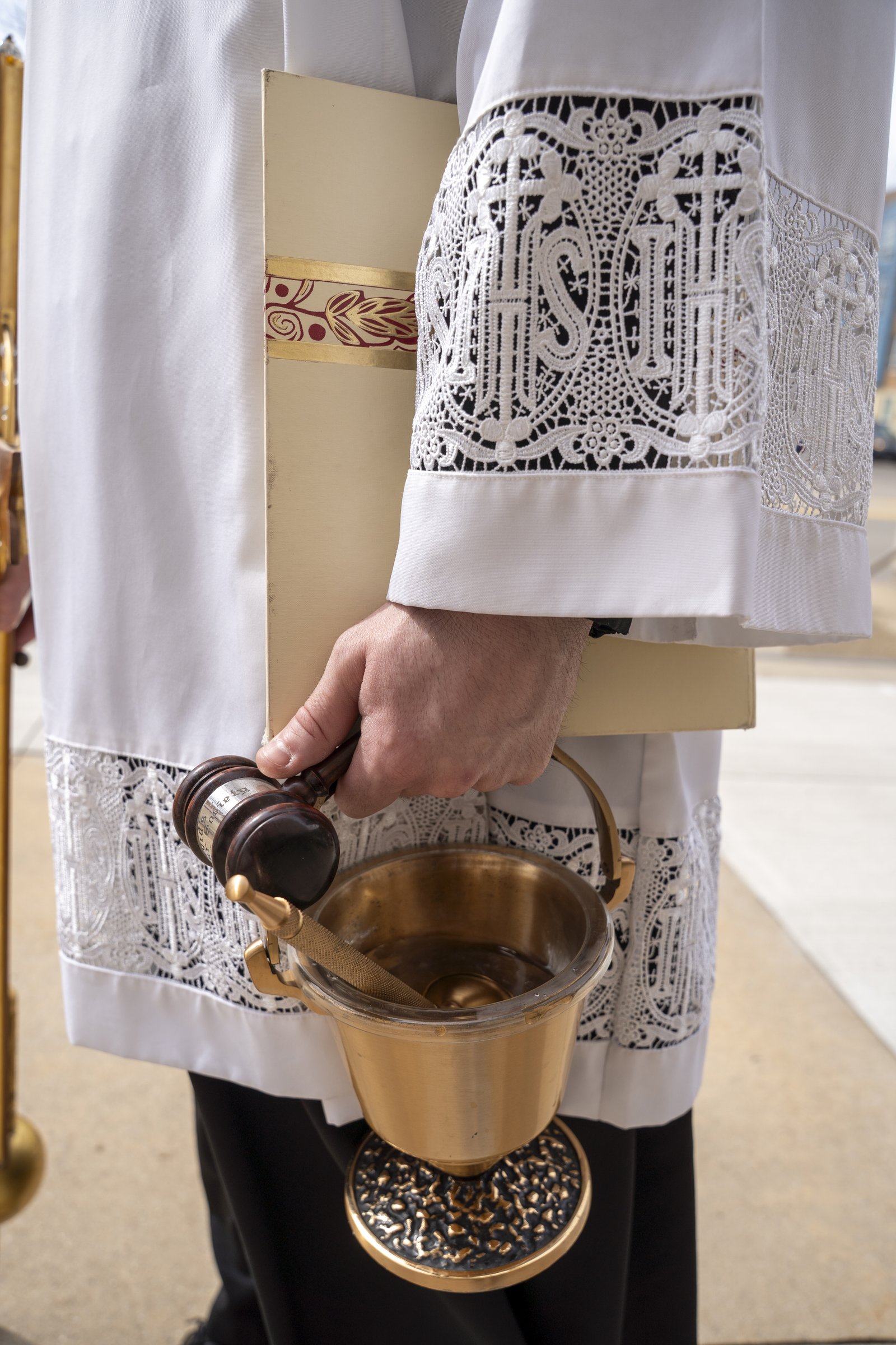 Fr. Derik Peterman holds a gavel and holy water, which Archbishop Weisenburger used during the opening rite of the installation Mass. (Valaurian Waller | Detroit Catholic)