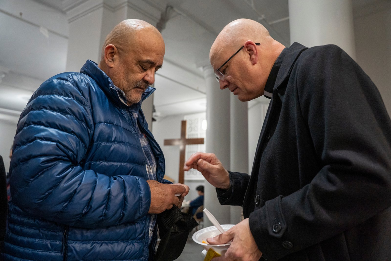 Archbishop Weisenburger offers a blessing to a man during a reception following Mass.