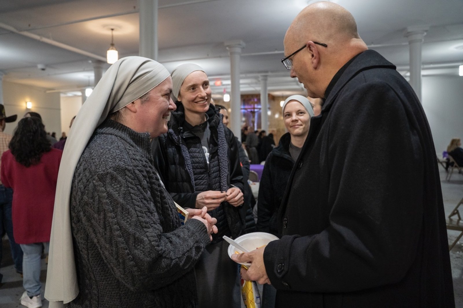 Archbishop Weisenburger greets members of the Society of Our Lady of the Most Holy Trinity (SOLT), who administer Holy Redeemer Parish and School, during a reception after Mass.