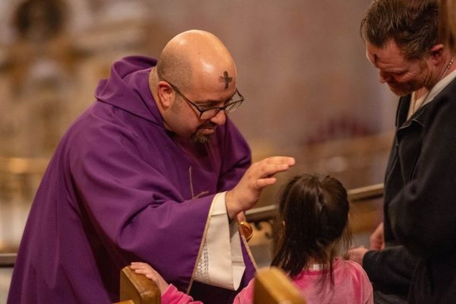 Fr. Sal Palazzolo blesses a young girl during Communion during Ash Wednesday Mass at St. Aloysius Parish in downtown Detroit on Feb. 18.
