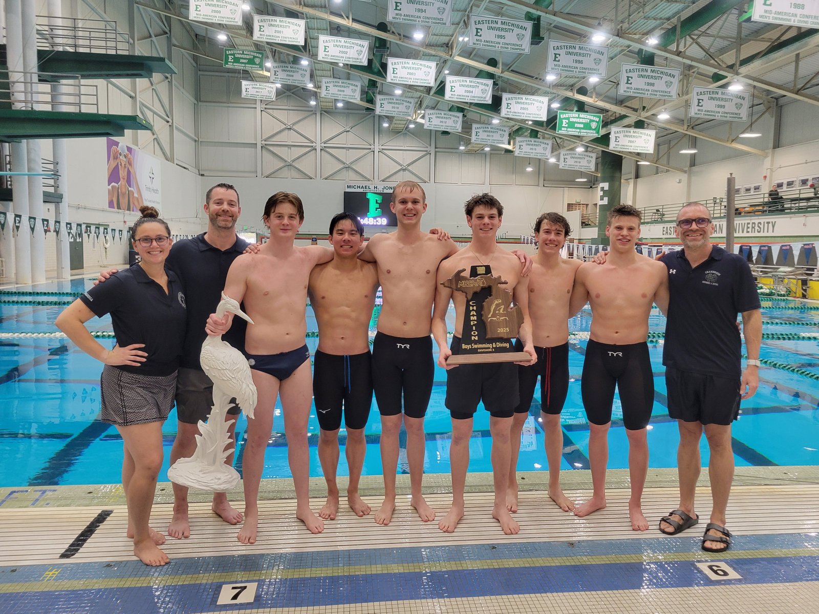 Cranbrook seniors and coaches stand on the deck of the Jones Natatorium, showing off their state championship trophy. The Cranes won the meet decisively, scoring 357 points and winning four of the 12 events. (Photo courtesy of Lillian Tao)