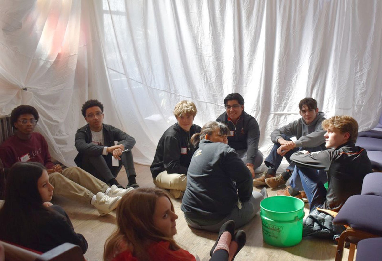 A group of students participates in a refugee camp simulation, receiving rationed food, water, and tent space to replicate real-life conditions.