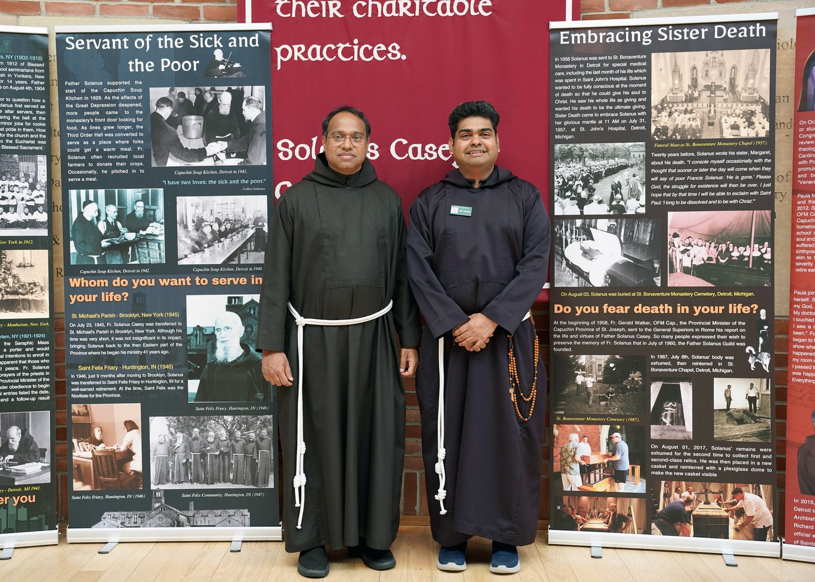 Bro. Benoy Joseph, OFM Cap, the center's director (left), and Bro. Daniel Emmanuel Victor, OFM Cap – who is responsible for the traveling museum – pose in front of the educational banners that are part of the exhibit.