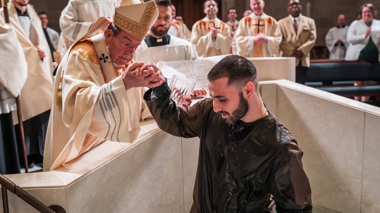 Archbishop Vigneron helps a catechumen out of the baptismal waters after baptizing him during the Easter Vigil on April 8, 2023, at the Cathedral of the Most Blessed Sacrament. (Valaurian Waller | Detroit Catholic)
