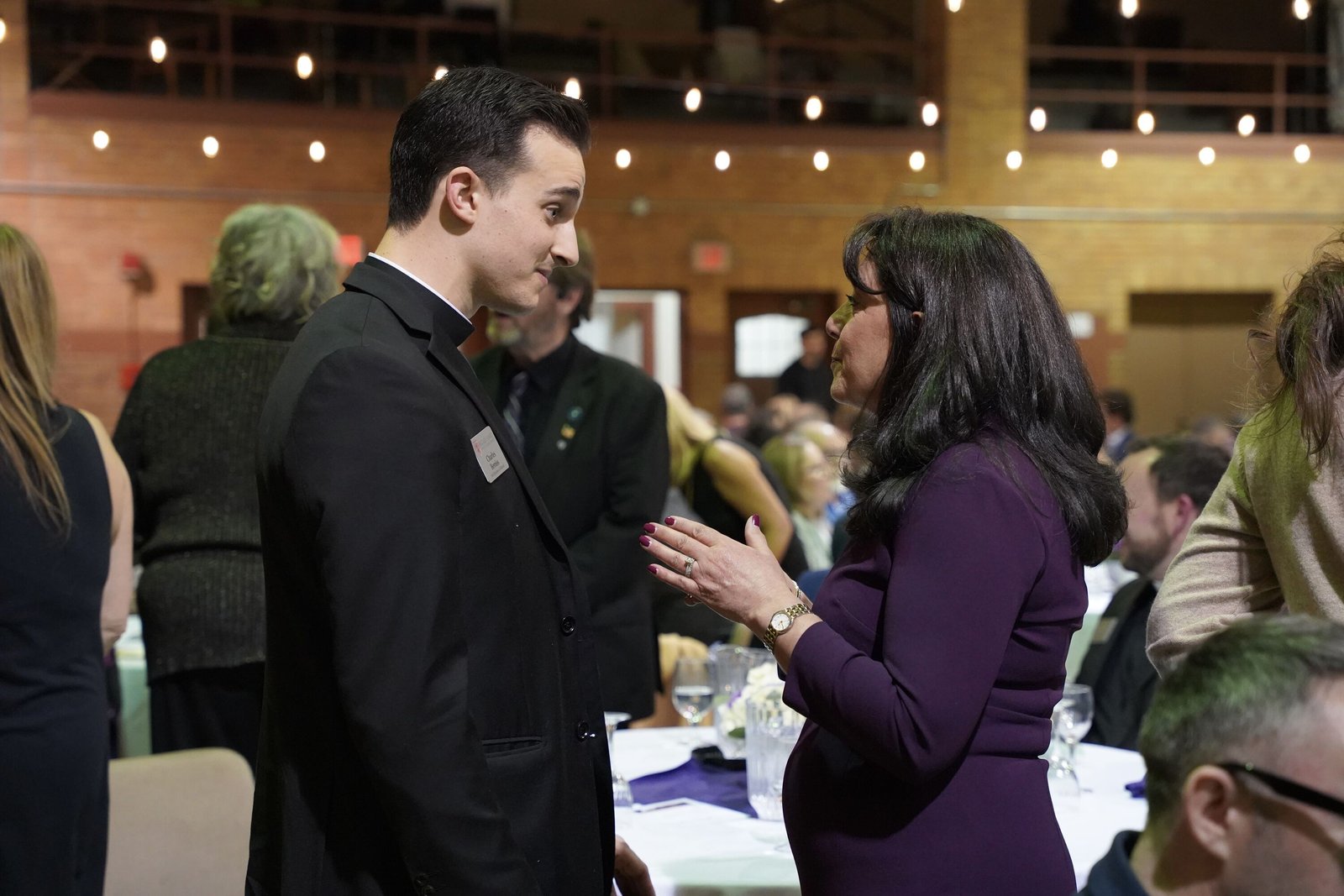 Detroit seminarian Charles Bemiss, left, one of the co-chairs of this year's Dinner for Life, chats with guests during the fundraising dinner in Sacred Heart's gymnasium.