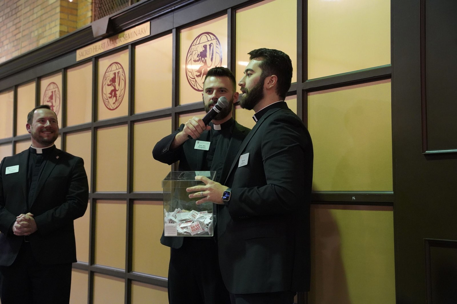 El diácono Jim Musgrave, al centro, sostiene un micrófono mientras se anuncia el nombre del ganador de la rifa.