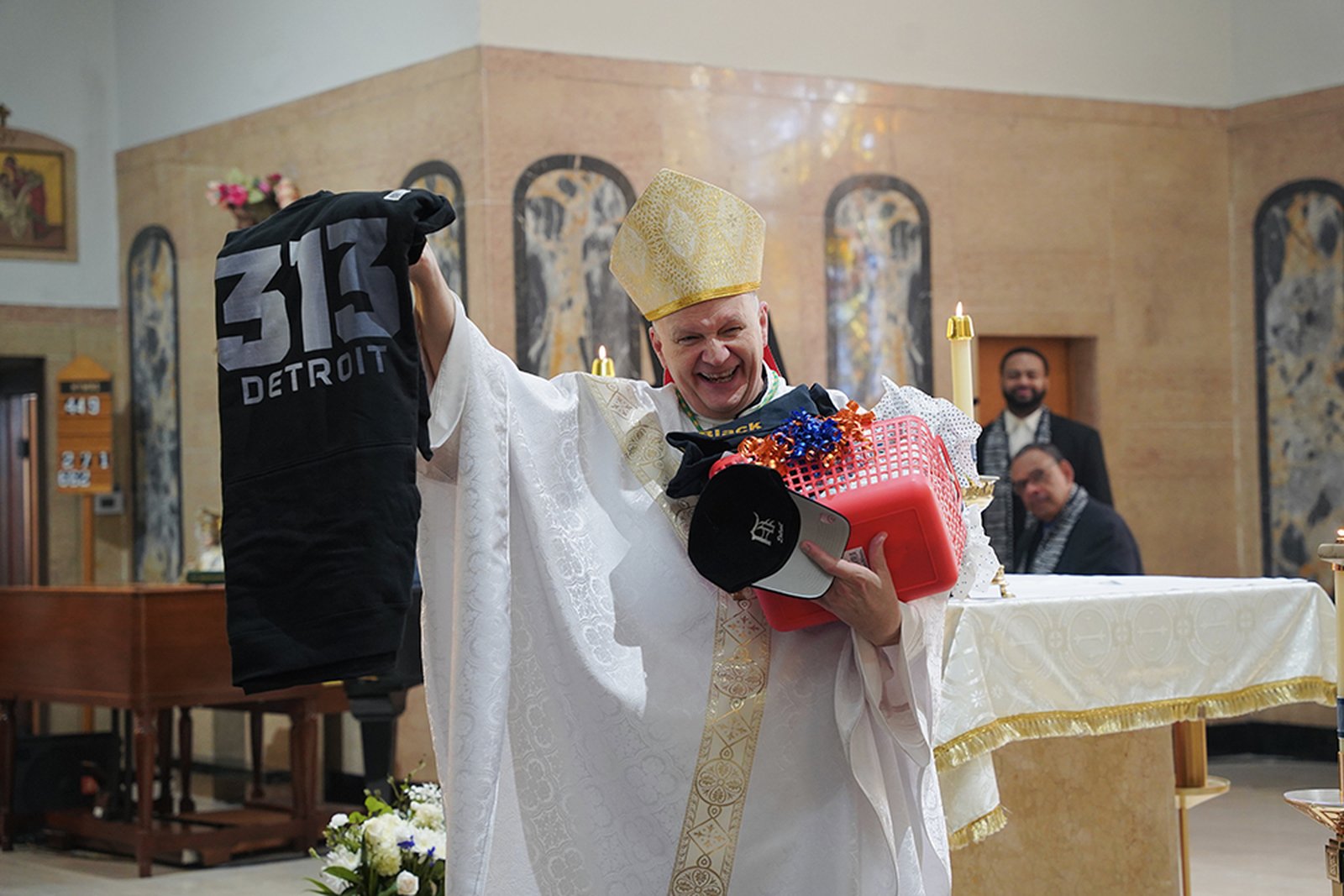 Archbishop Edward J. Weisenburger holds up some of the Detroit-themed gifts he received from parishioners at St. Moses the Black Parish in Detroit, where the archbishop celebrated Mass on May 18 as part of his tour of welcome Masses around the Archdiocese of Detroit. Archbishop Weisenburger was installed as archbishop of Detroit two months ago, on March 18. (Photos by Izzy Cortese | Detroit Catholic)