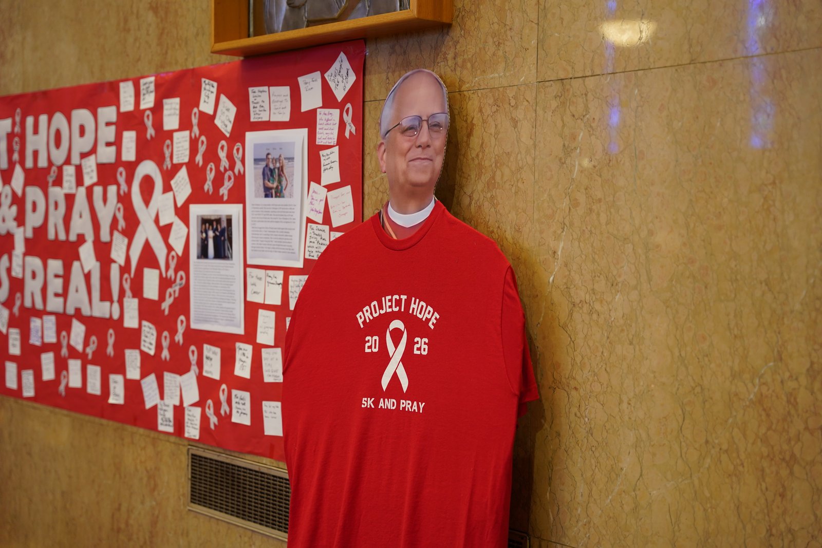 Una figura de cartón a tamaño real del papa León XIV viste una camiseta roja del «Proyecto Esperanza» (Project Hope), junto a un periódico mural que exhibe oraciones y mensajes de esperanza para dos feligreses, Bruce Hubbel y Jamie Dempsey, quienes están luchando contra el cáncer.