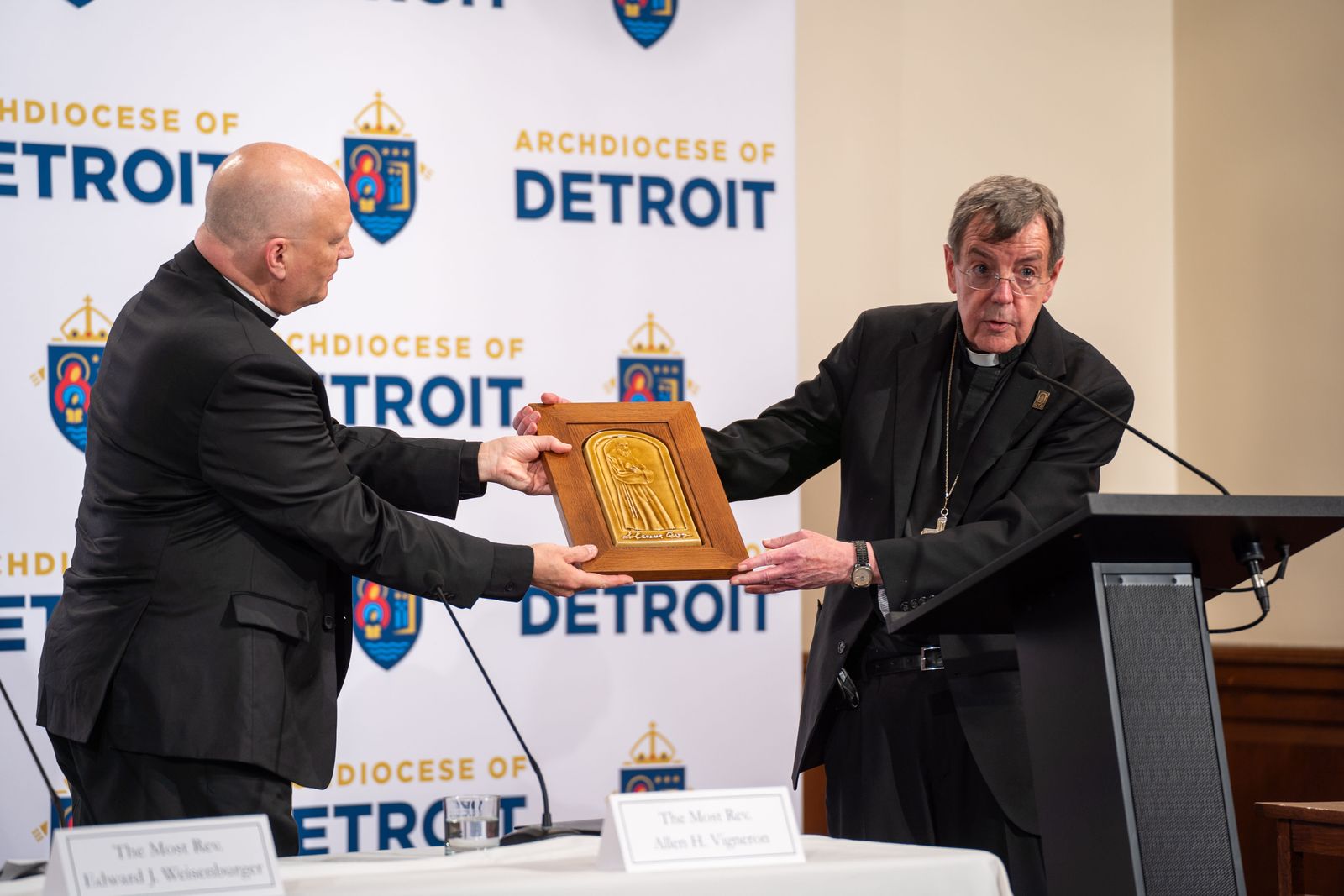 Archbishop Allen H. Vigneron, right, gives Archbishop-elect Edward J. Weisenburger a Pewabic tile with an image of Blessed Solanus Casey, Detroit's native saint. Sacred Heart Major Seminary, where the introductory press conference took place, has the second-largest installation of Pewabic tile in the United States.