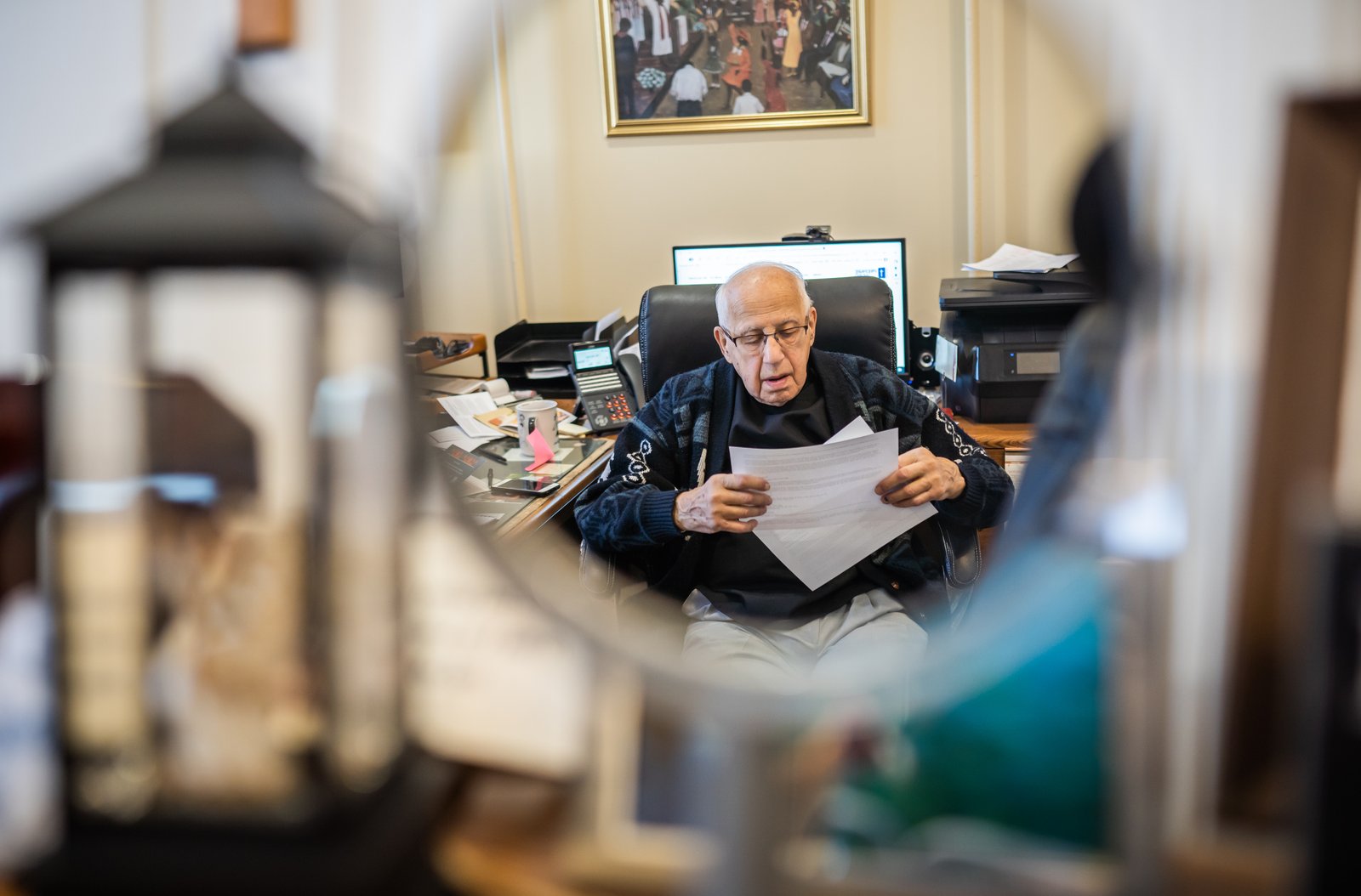 Fr. Thomas goes over paperwork in his office at Sacred Heart Parish in Detroit, where he began serving as pastor in 1968. At 91, he relies more these days on his parish staff, but says he's never considered retiring.