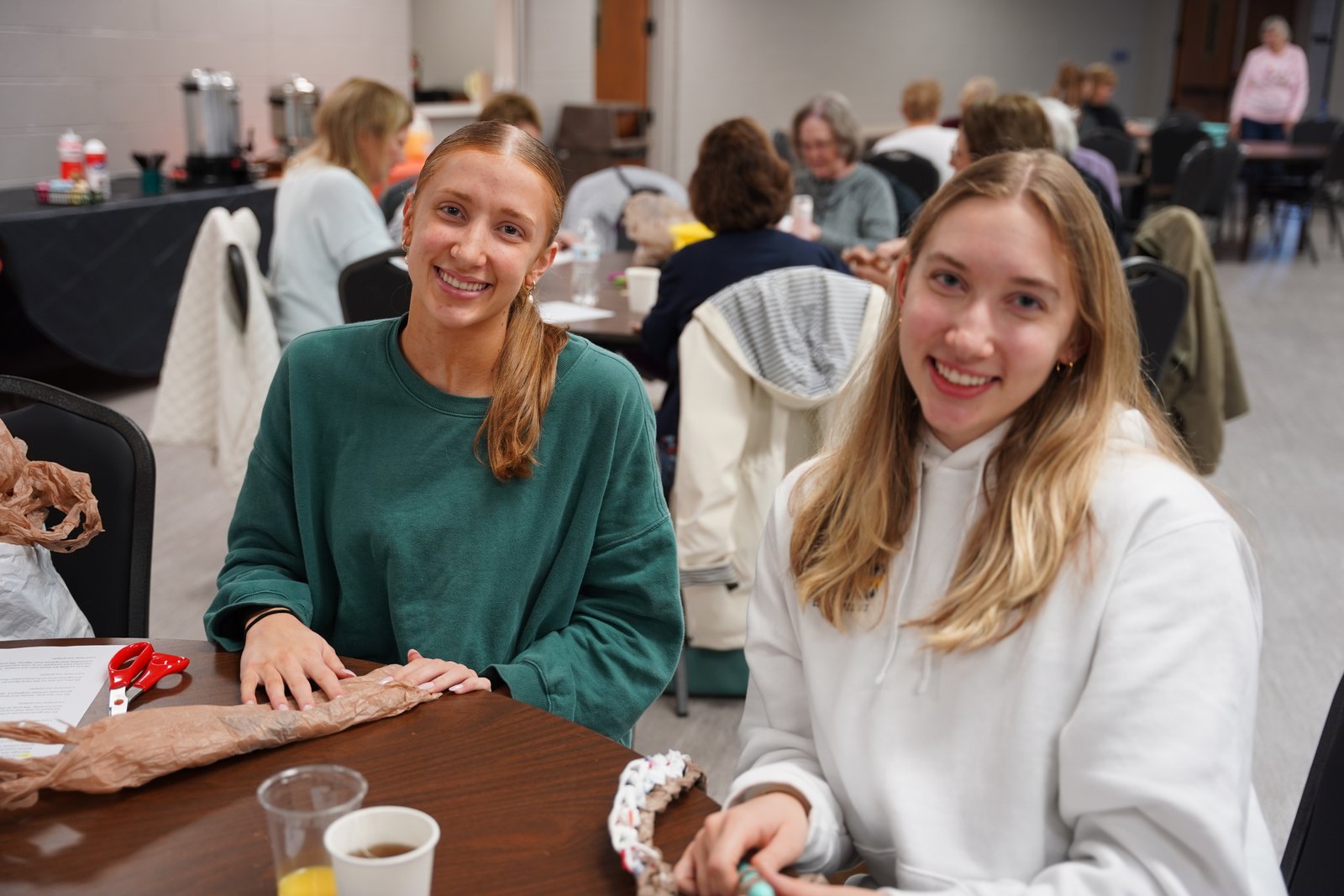 Left to right, Courtney and Mackenzie Corbin prepare and crochet plastic yarn, or "plarn," from grocery bags to assemble mats and pillows. (Maggie Sicilia | Detroit Catholic)